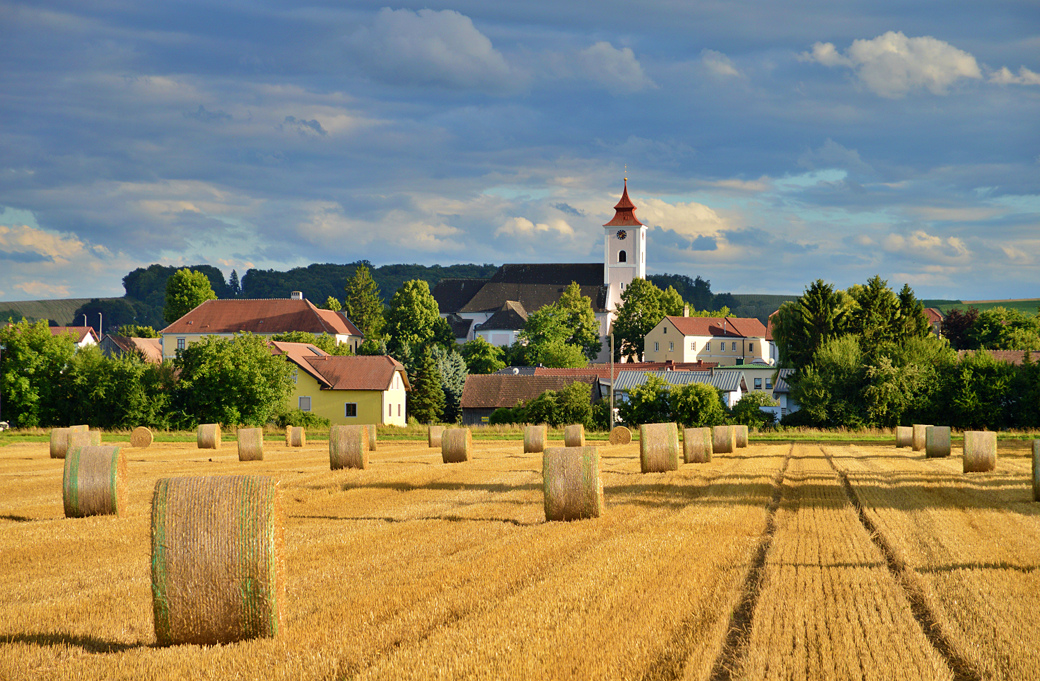 Landschaft mit Strohballen und Kirche in Michelhausen.