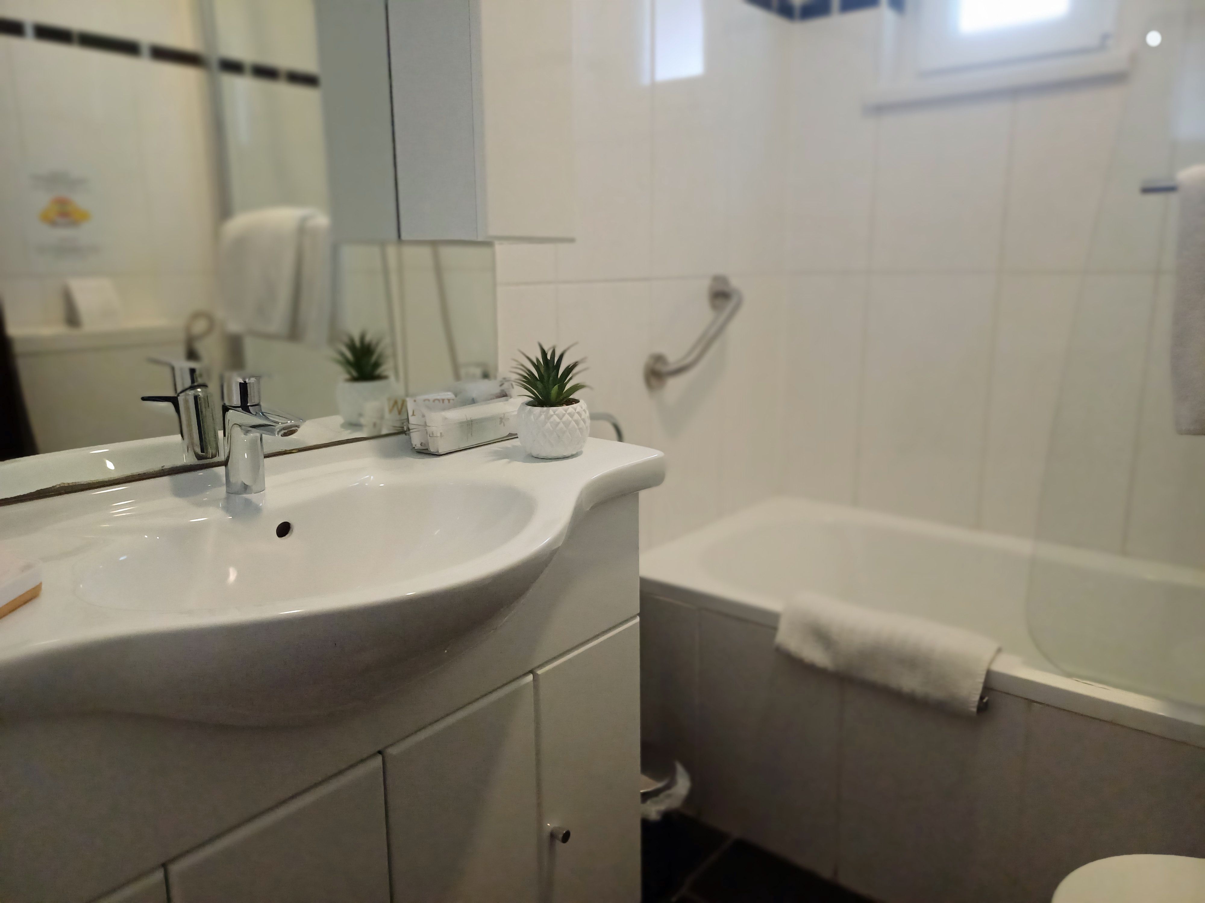 Badezimmer mit Waschbecken, Spiegel, Badewanne und Handtuch.