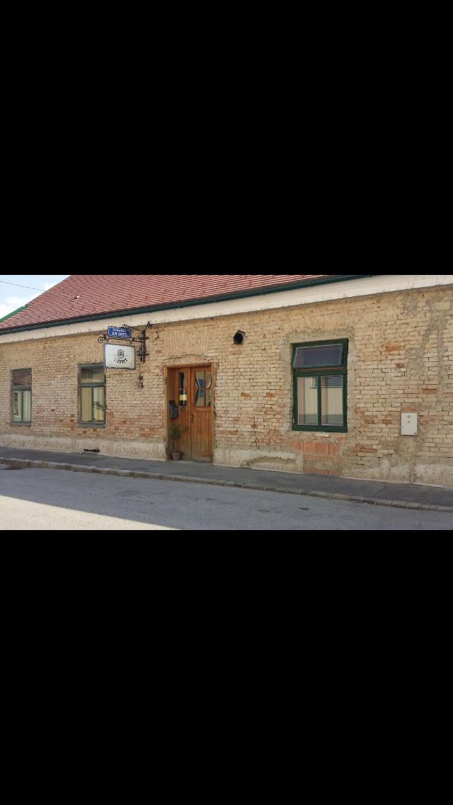 Außenansicht eines alten Gasthauses mit Ziegeldach und Backsteinfassade.