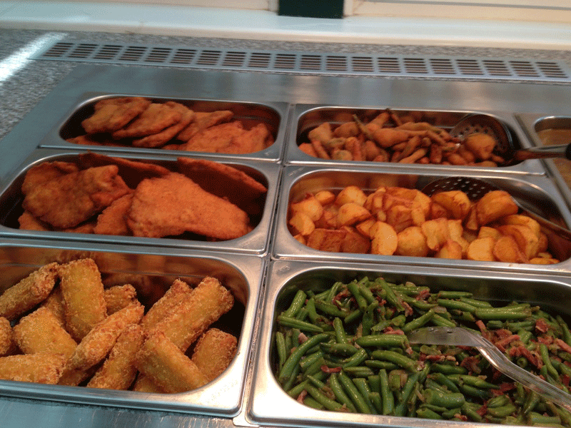 Buffet mit panierten Speisen, Kartoffeln und grünen Bohnen.