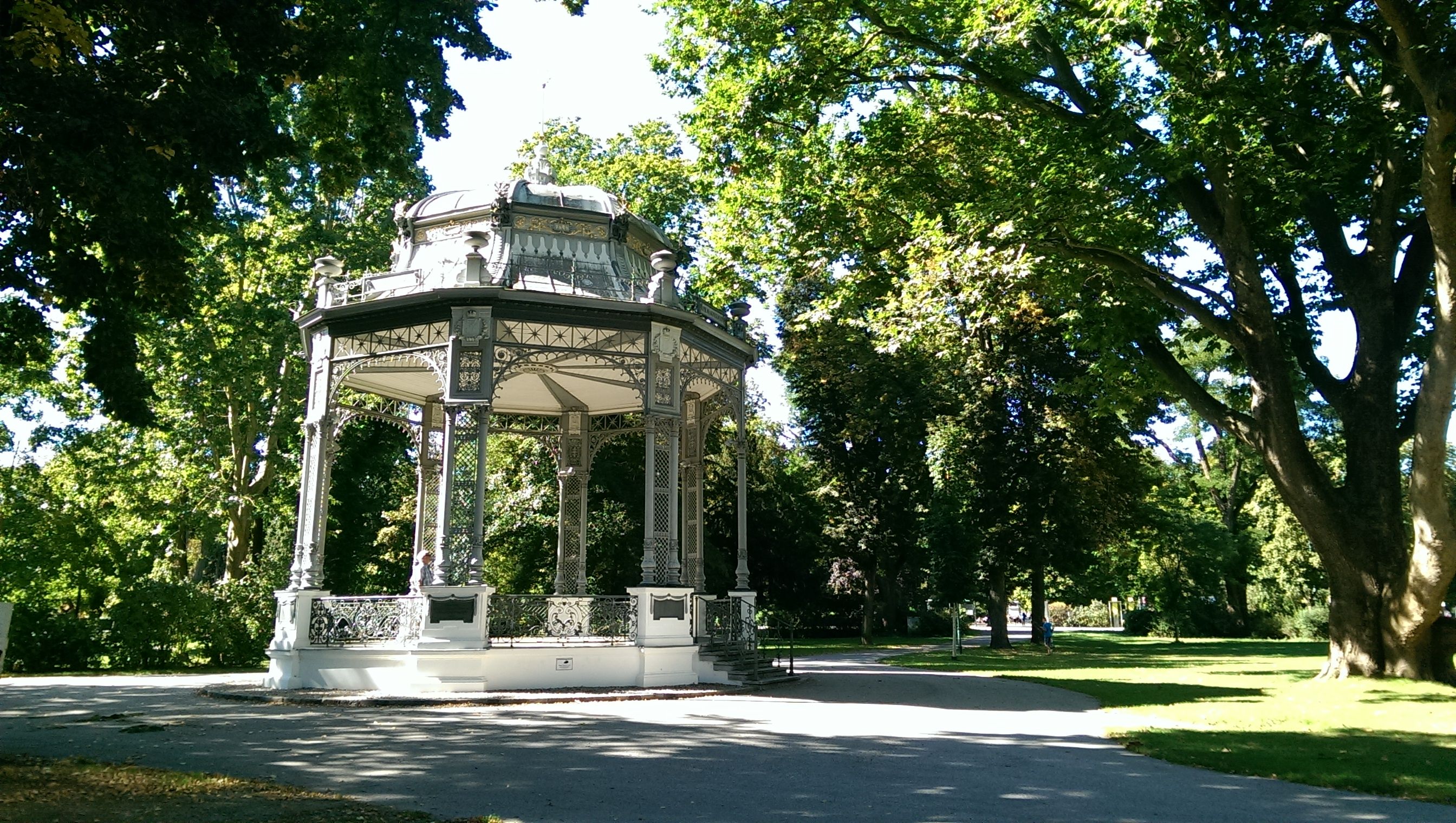 Ein dekorativer Pavillon im Stadtpark von Krems, umgeben von grünen Bäumen und einem Gehweg.