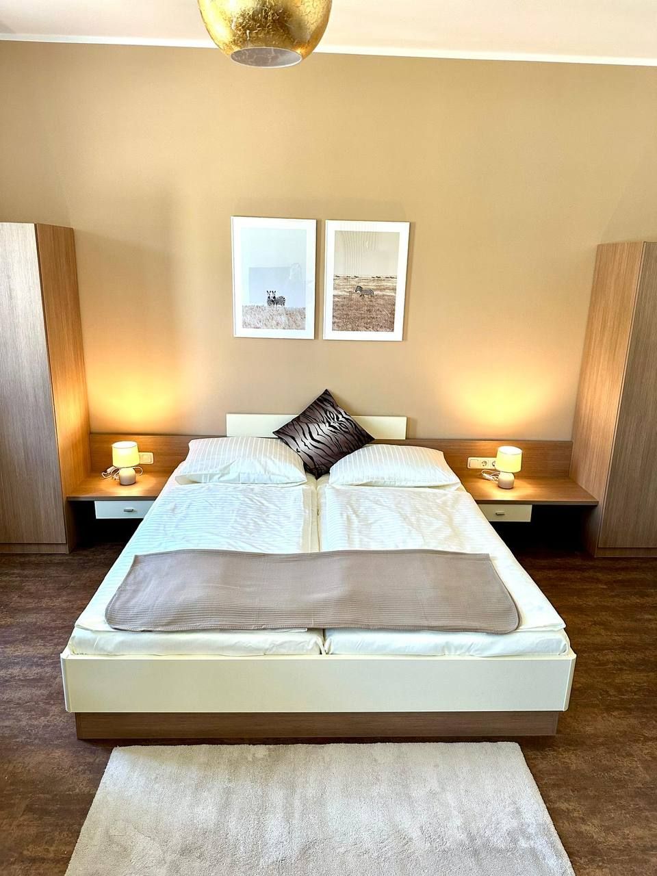 Modern bedroom with double bed, two bedside tables and wall pictures.