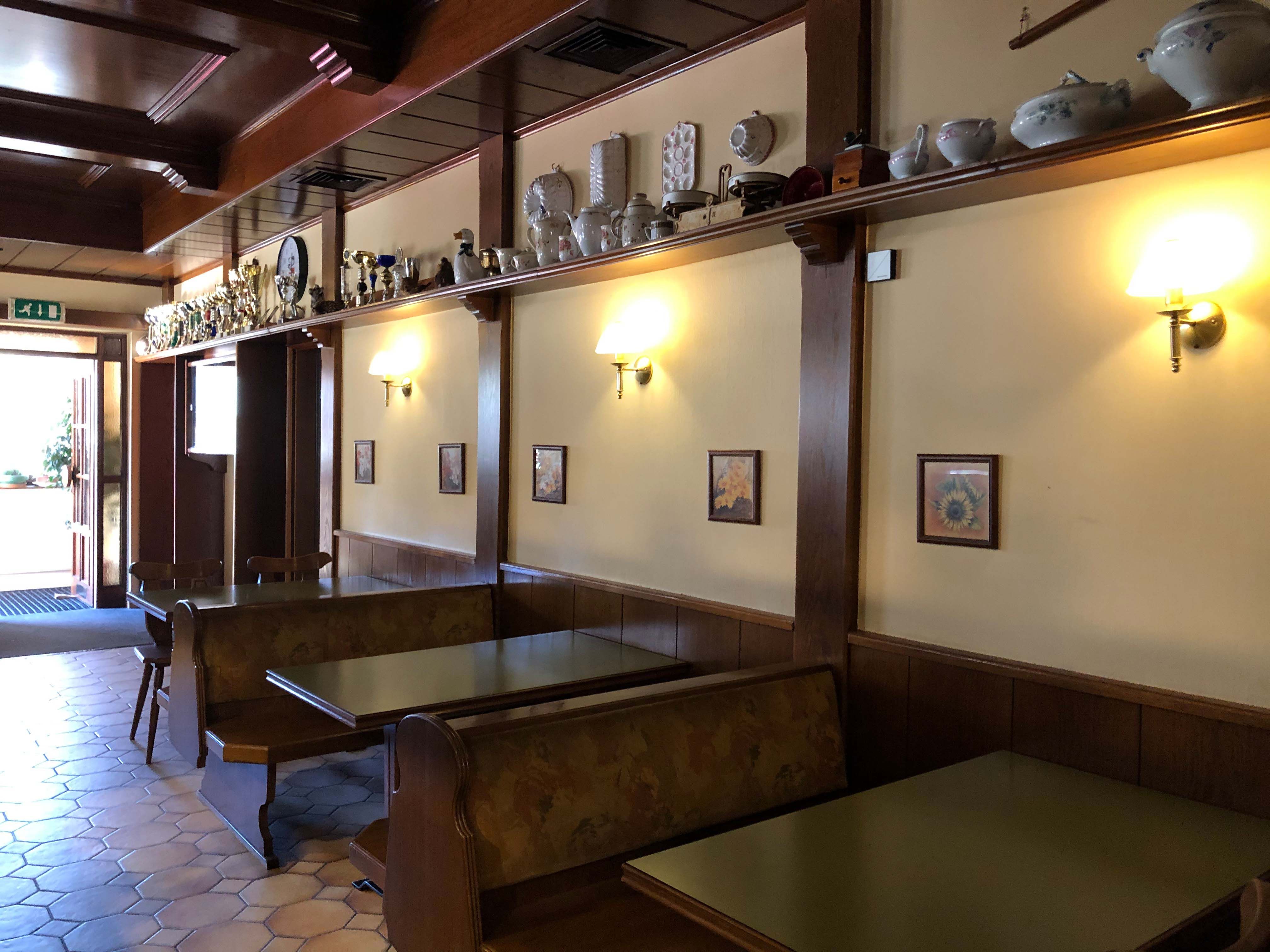 Innenansicht eines traditionellen Gasthauses mit Holzmöbeln und Dekorationen auf einem Regal.