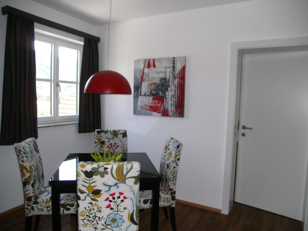 Essbereich mit floral gemusterten Stühlen, roter Hängelampe und modernem Kunstwerk an der Wand.