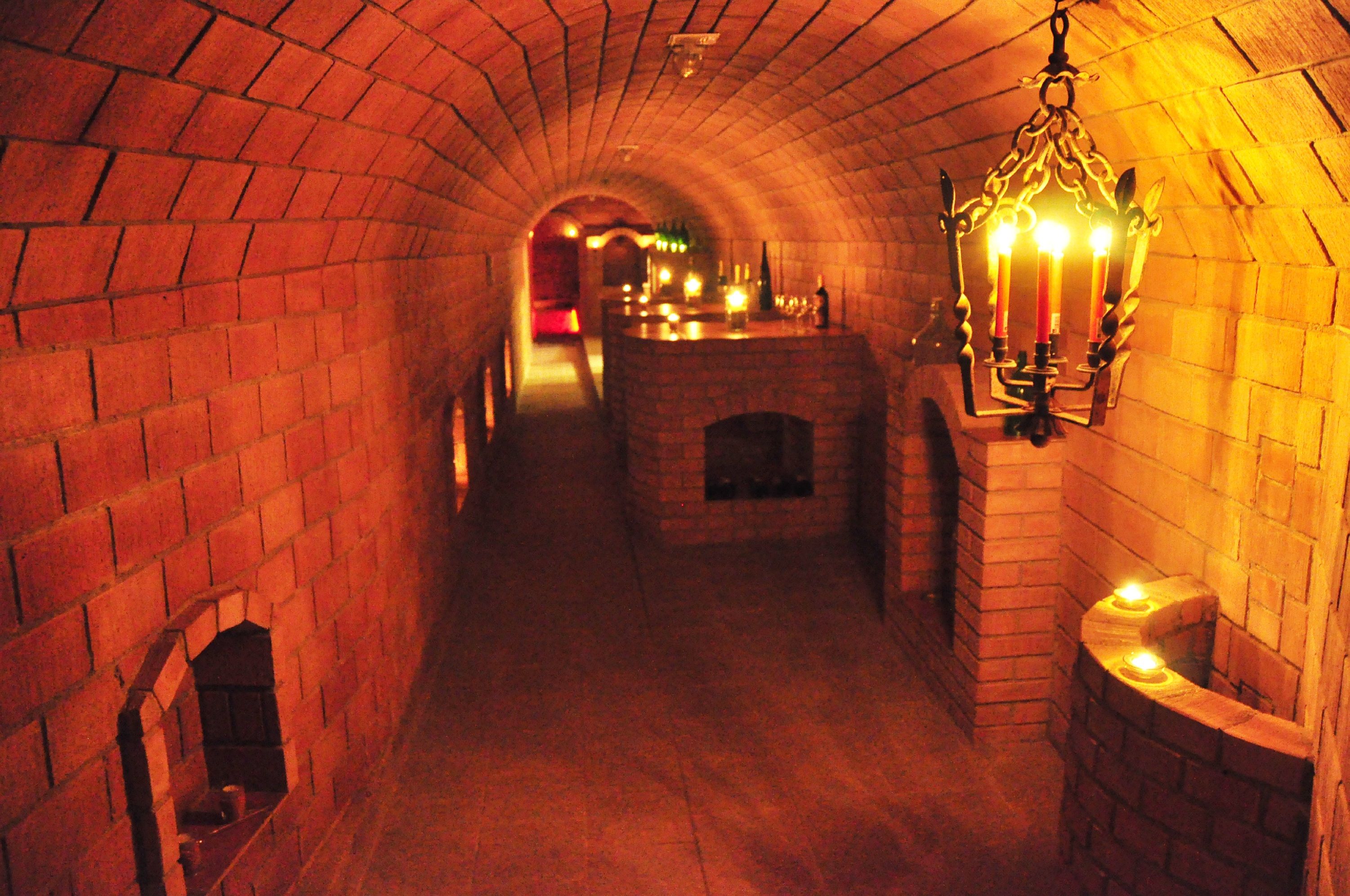 Ein beleuchteter Weinkeller mit Ziegelwänden und Kerzenlicht.