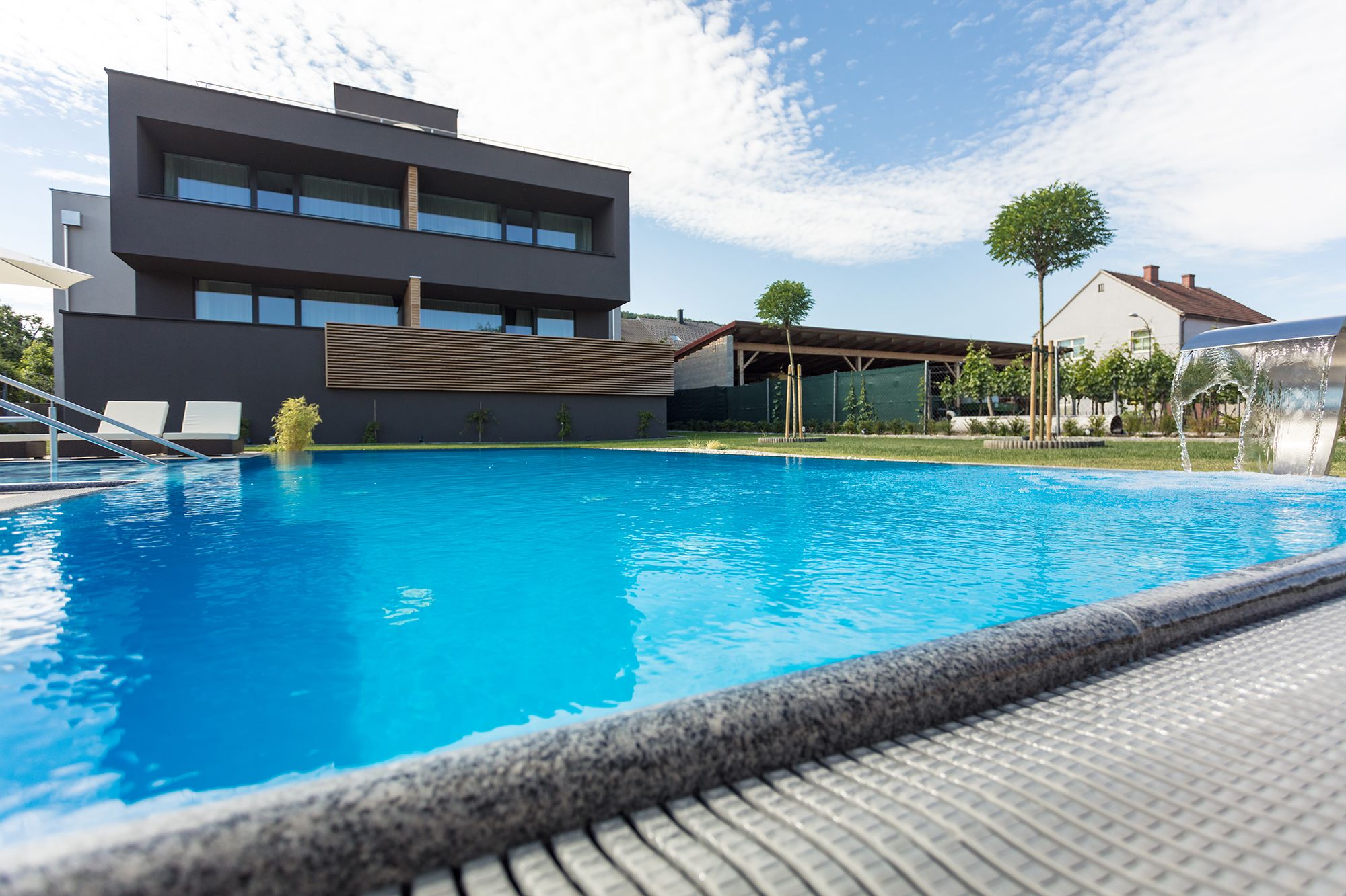Modernes Gebäude mit Pool im Vordergrund und blauem Himmel im Hintergrund.