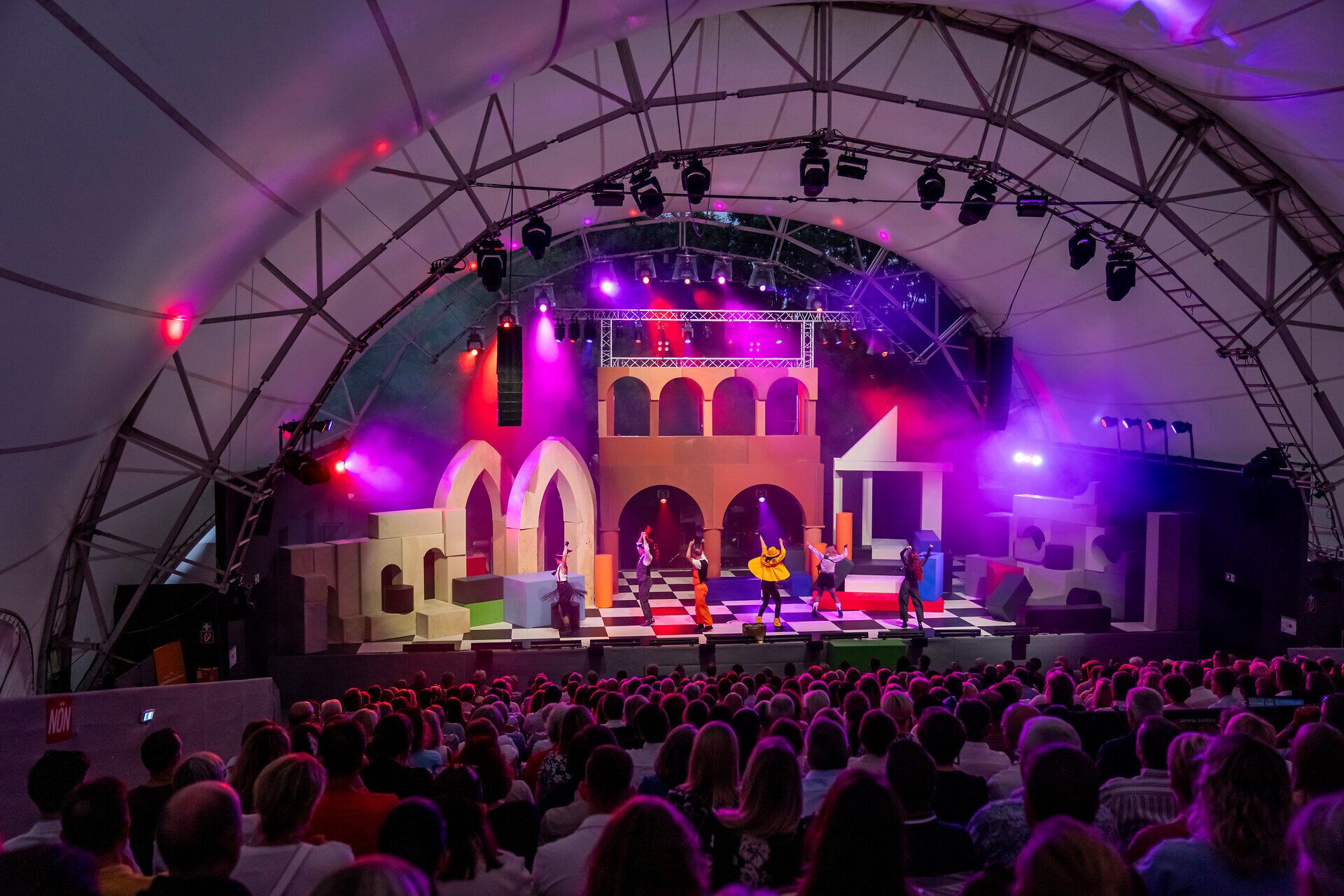 Die Bühne erstrahlt in bunten Lichtern, während talentierte Künstler mit Musik und Tanz das Publikum verzaubern. Die fröhliche Atmosphäre und die beeindruckende Kulisse schaffen ein unvergessliches Erlebnis für alle Besucher. Genießen Sie die kulturellen Höhepunkte in dieser malerischen Umgebung.