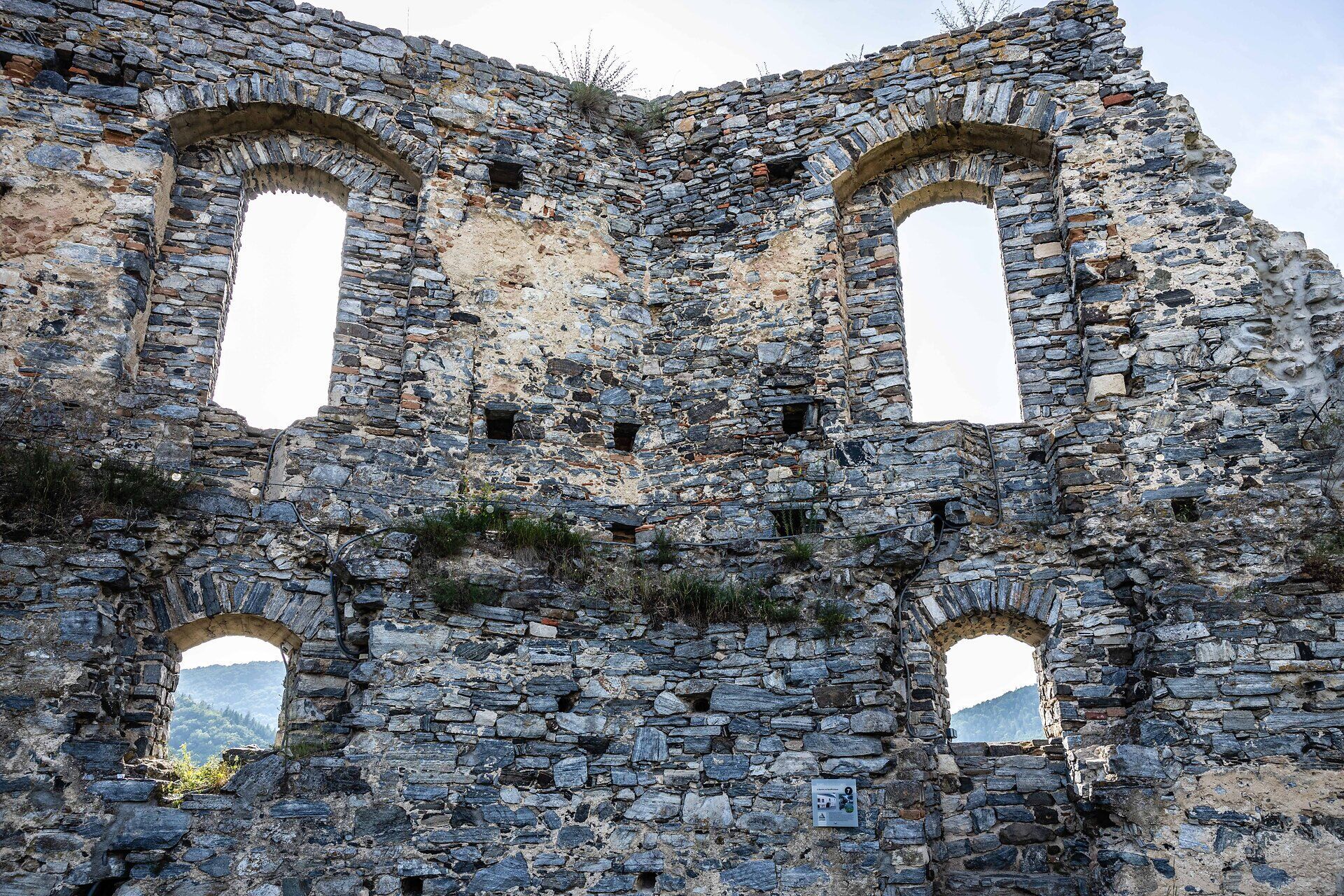 Eine alte Ruinenmauer mit vier Fensterauslassungen.
