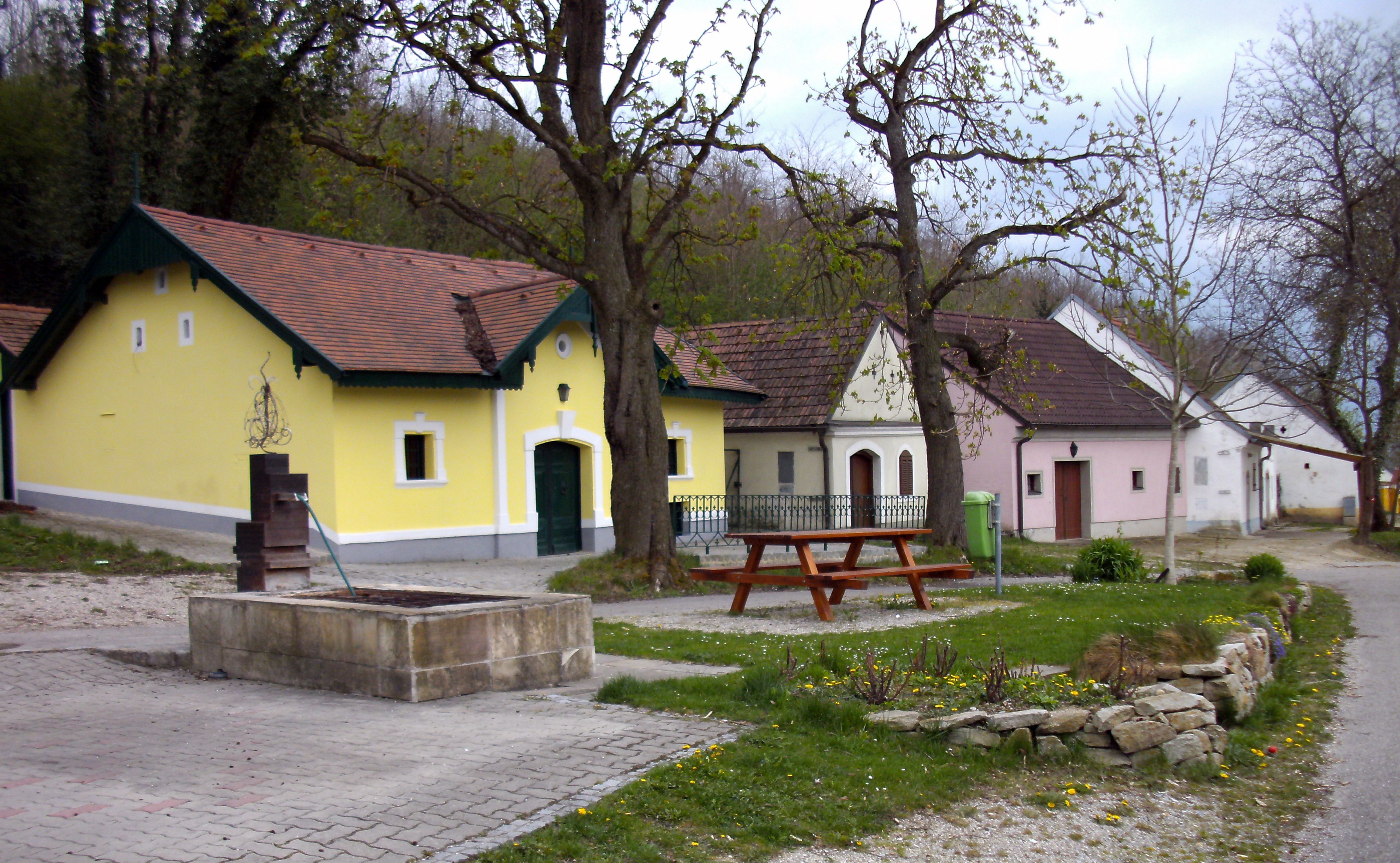 Kellergasse in Absdorf mit bunten Häusern und Bäumen.