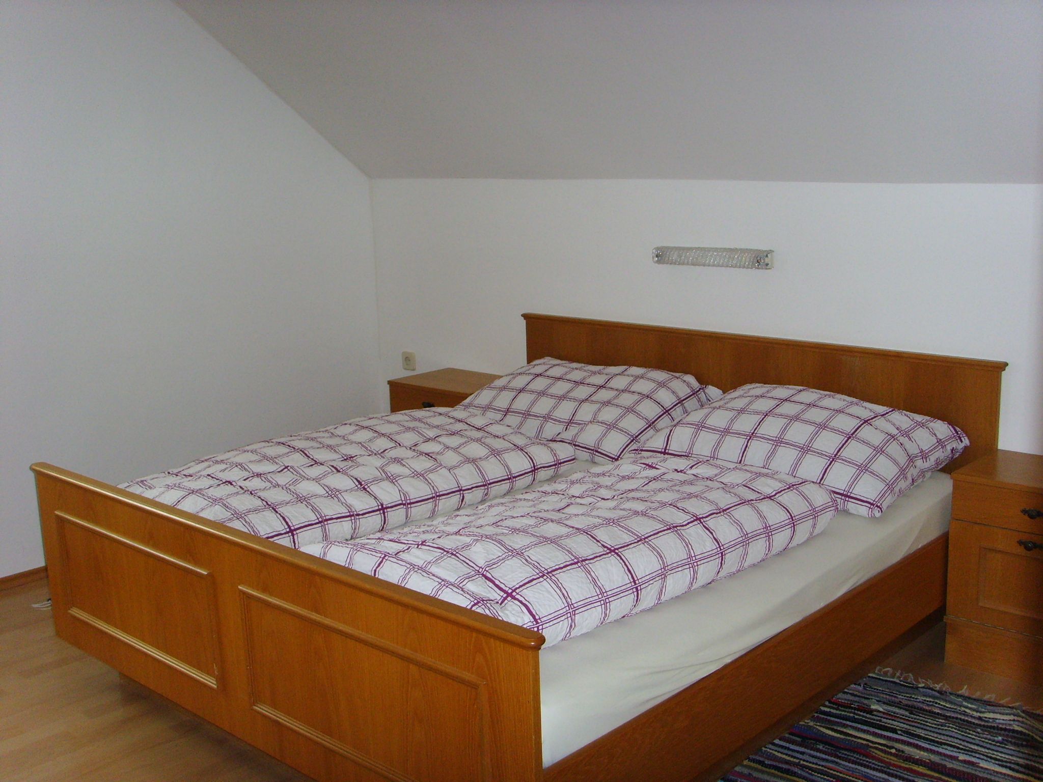 Schlafzimmer mit Holzbett und kariertem Bettzeug.