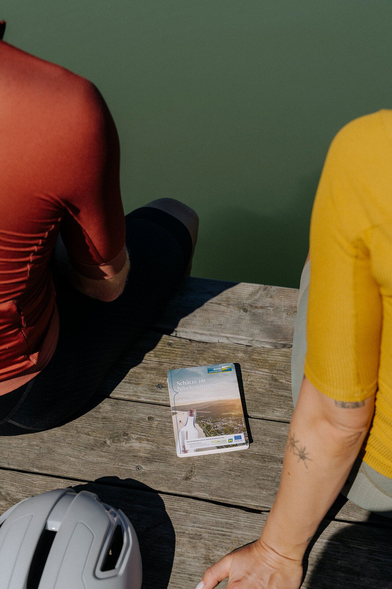 Die Schatzkarte Nibelungengau liegt auf einem Holzsteg an der Donau zwischen 2 Radfahrern. 