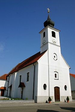 Fehér templom toronnyal és vörös tetővel a kék égbolton.