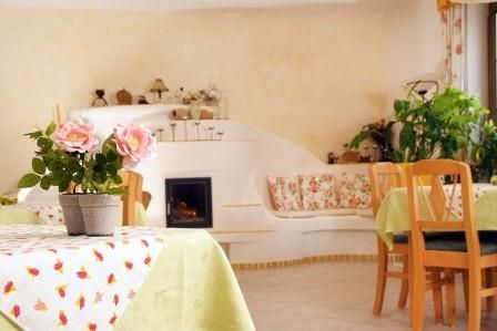 Gemütlicher Frühstücksraum mit Holzmöbeln, Pflanzen und einem kleinen Kamin.