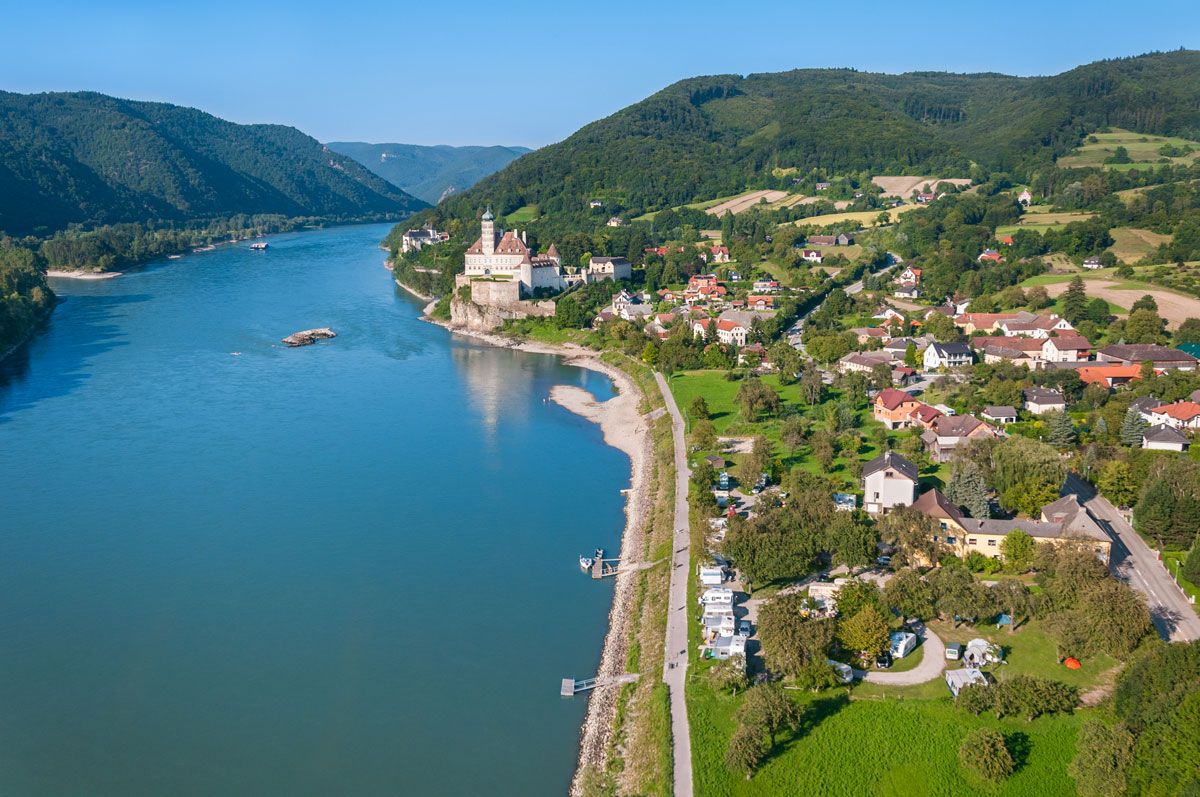 Luftaufnahme von Schönbühel an der Donau mit Schloss und umliegender Landschaft.