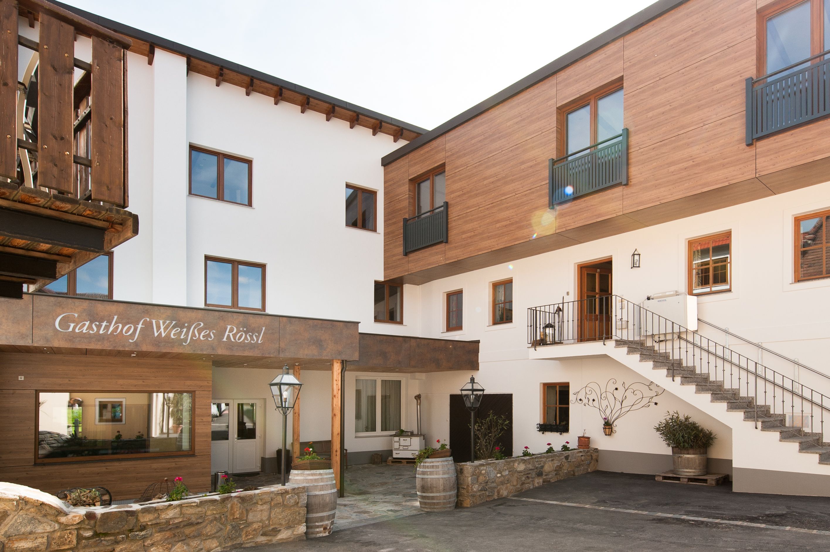Außenansicht eines Gasthofs mit Holz- und weißen Fassaden, Treppe und Dekorationen.