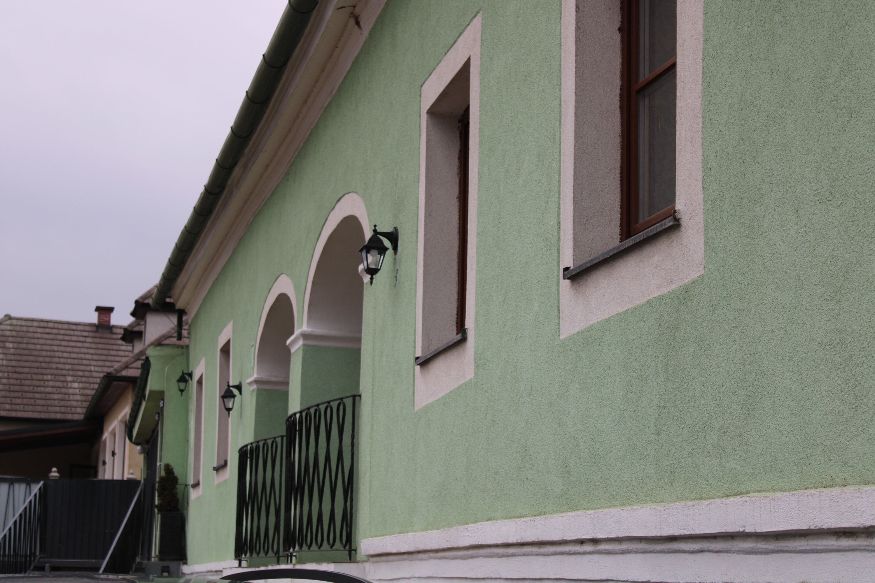 Grünes Gebäude mit weißen Fensterrahmen und Laternen.