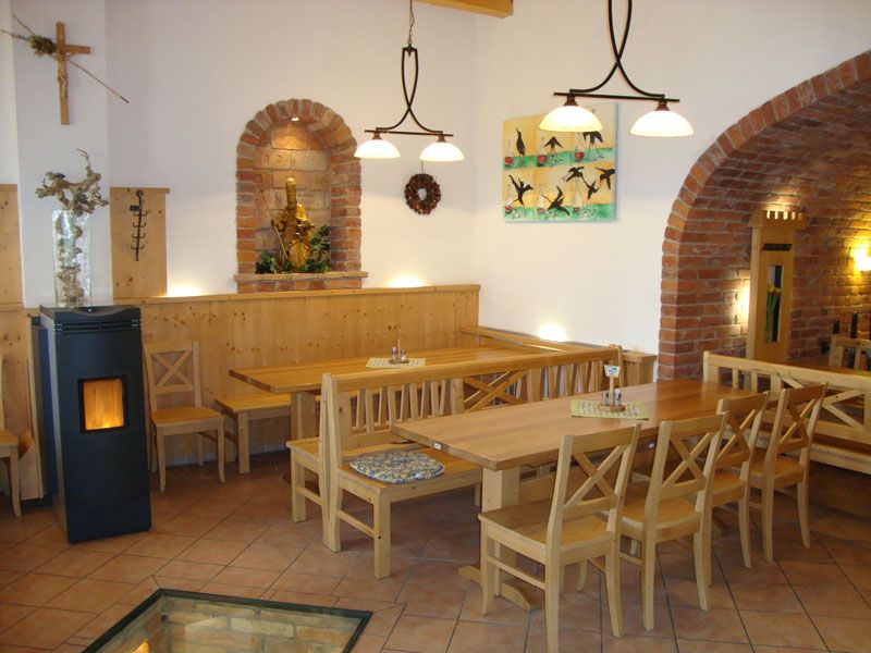 Gemütlicher Innenraum eines Heurigen mit Holzmöbeln und Backsteinbögen.