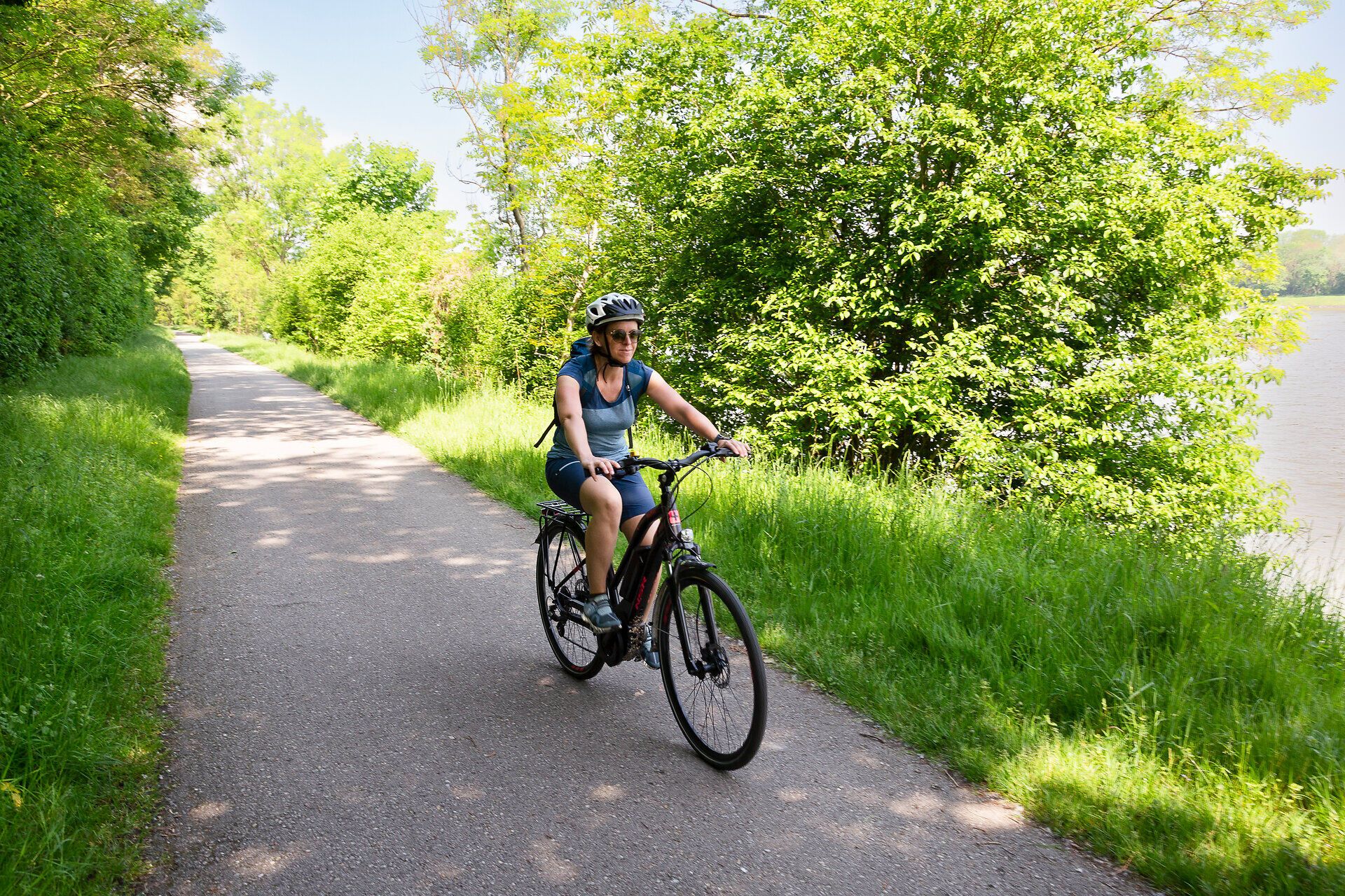Radfahrerin auf asphaltiertem Waldweg.