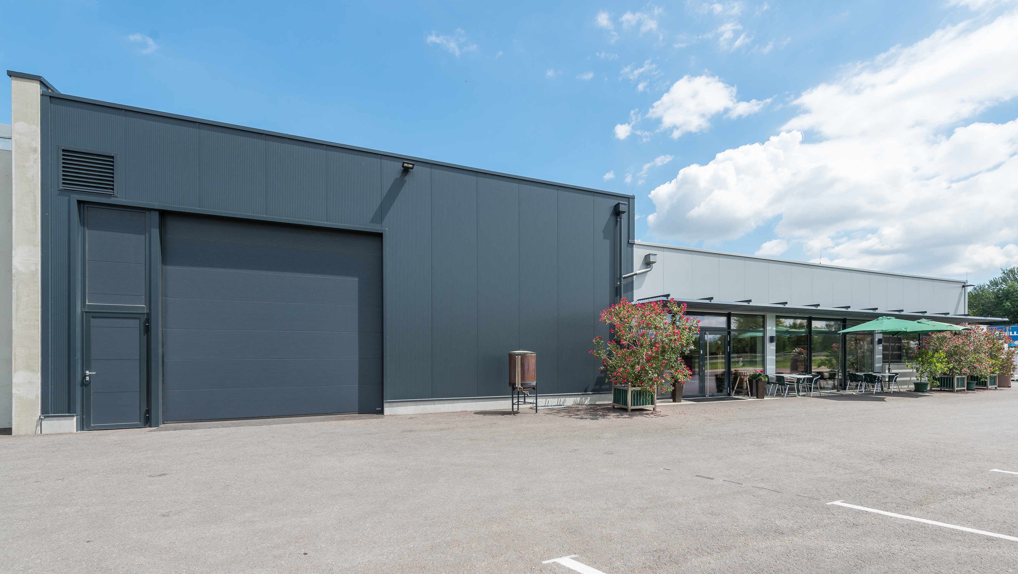Modern industrial hall with glass front and terrace with sunshade.