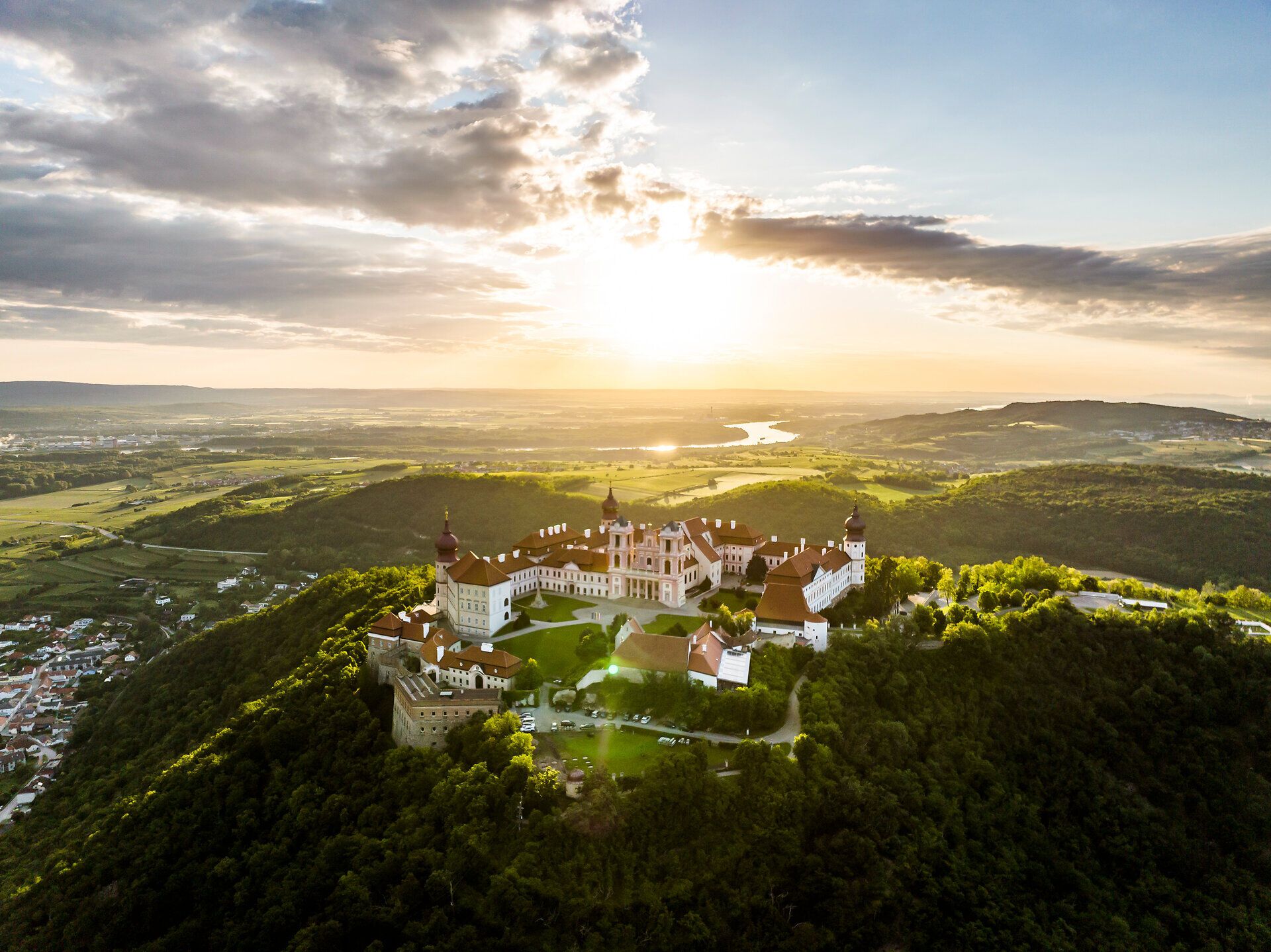 Hoch oben auf dem Hügel thront das Benediktinerstift Göttweig majestätisch über dem Donautal. Die sanften Hügel und die glitzernde Donau im Sonnenlicht schaffen eine malerische Kulisse, die zum Verweilen und Entdecken einlädt.