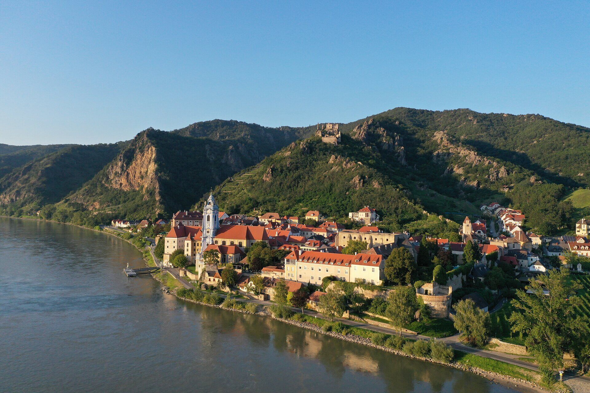 Die malerische Kulisse von Dürnstein, umgeben von sanften Hügeln und dem glitzernden Wasser der Donau, lädt zu einem unvergesslichen Sommerausflug ein. Die charmanten, bunten Häuser und die historische Ruine auf dem Berg schaffen eine Atmosphäre voller Romantik und Abenteuer.