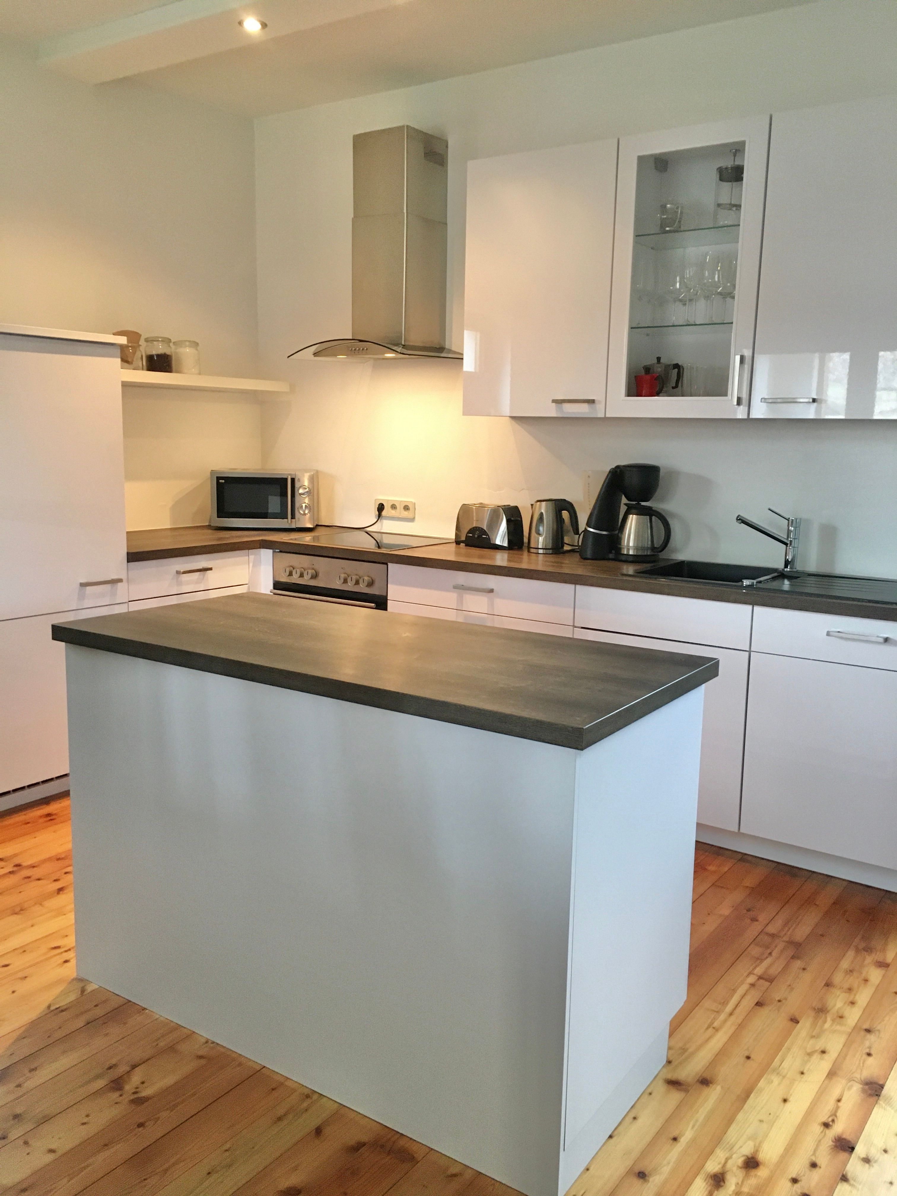 Moderne Küche mit Insel, weißen Schränken und Geräten.