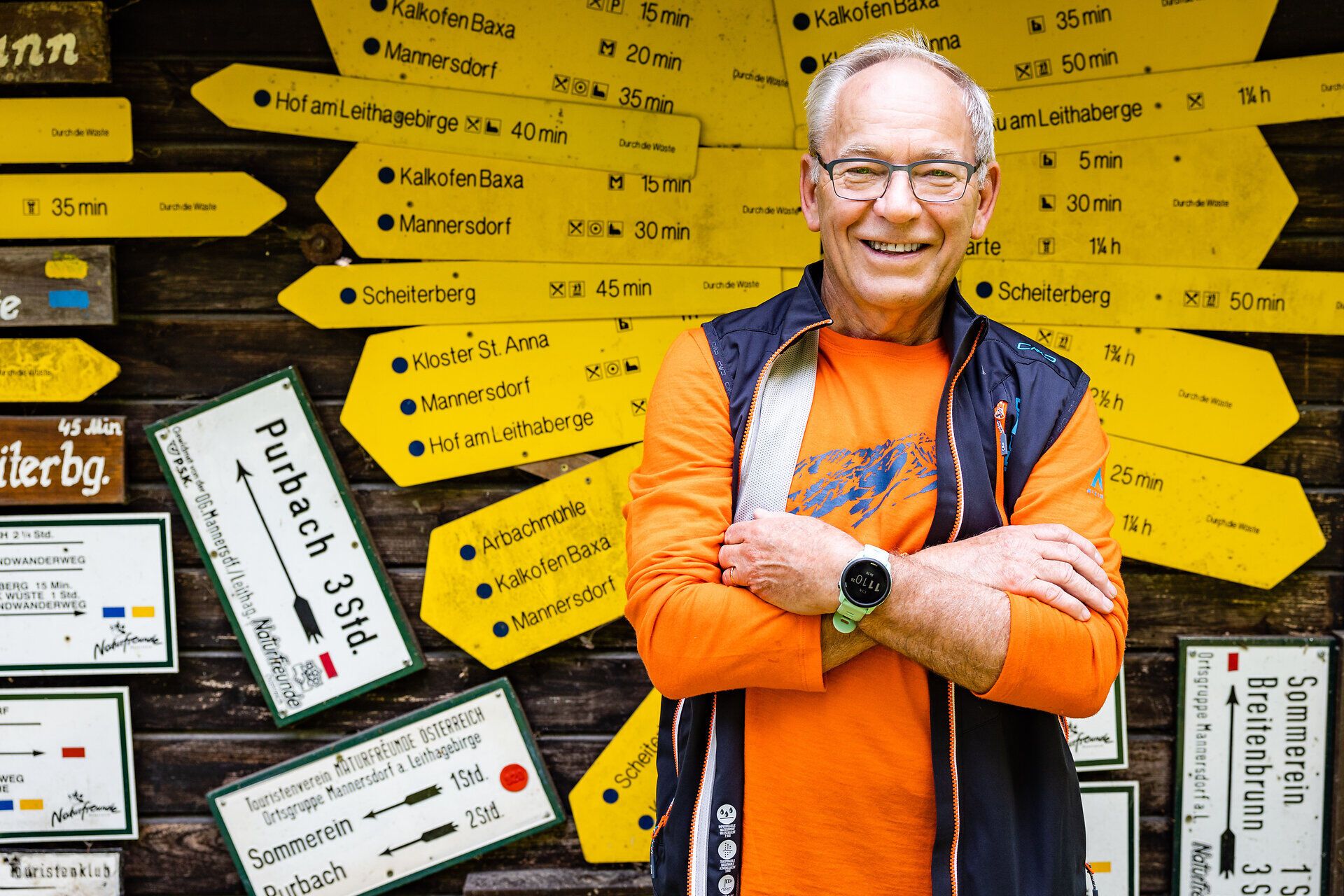 Mann steht vor einer Hütte im Wald mit alten Wanderschildern als Dekoration.