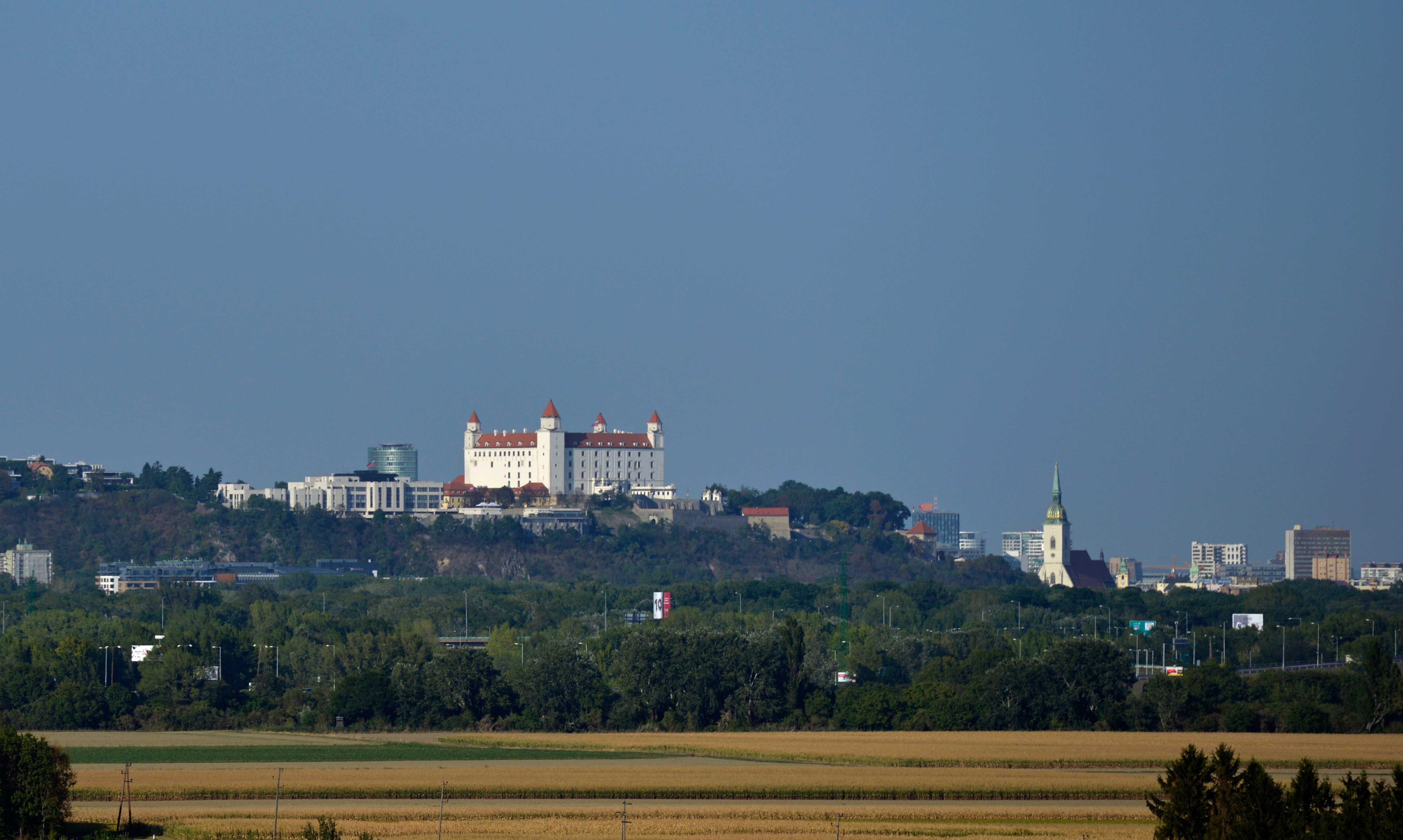 Blick auf die Burg Bratislava und die Stadt im Hintergrund, umgeben von grüner Landschaft.