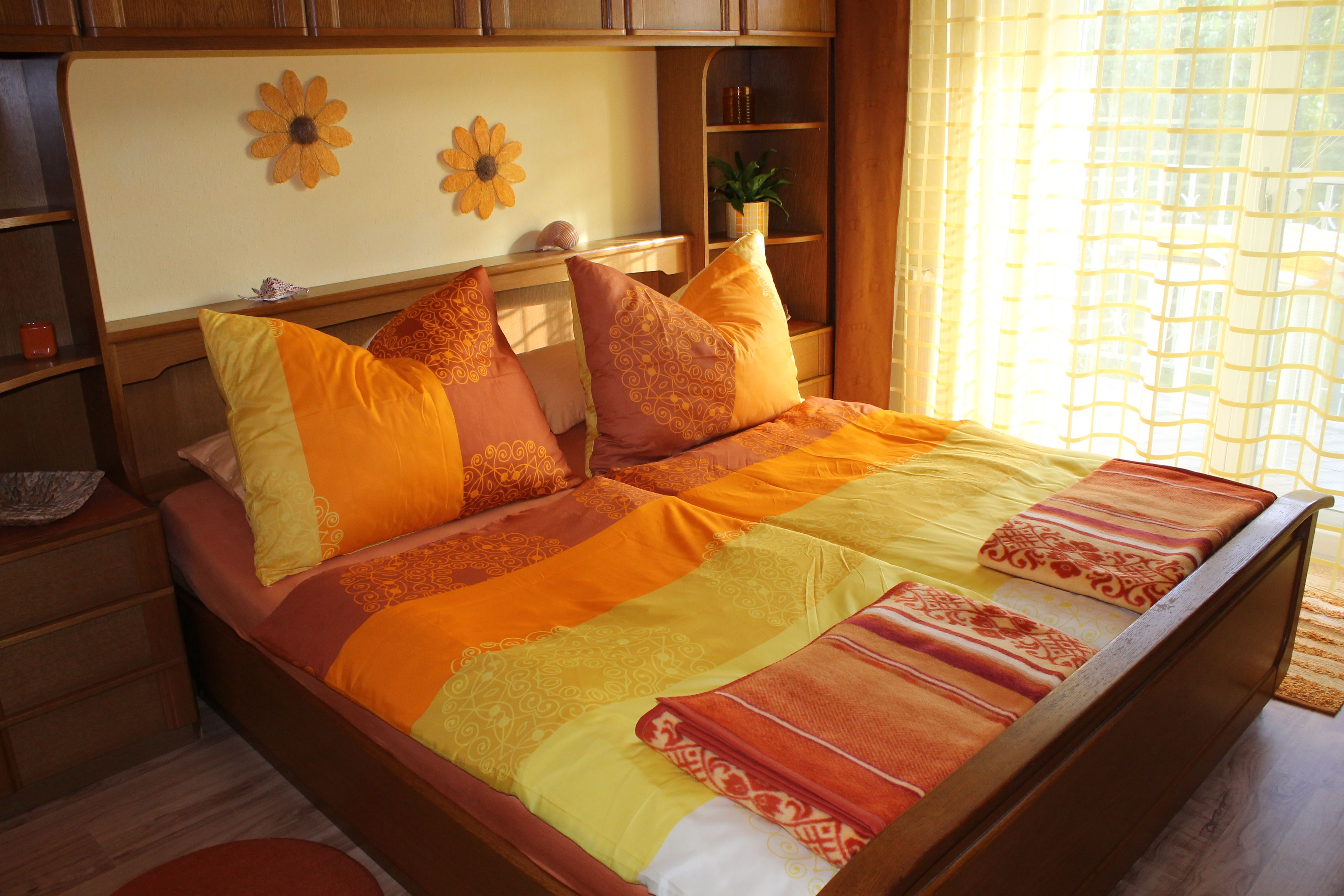 Cozy bedroom with sunflower decor and orange-yellow bed linen.
