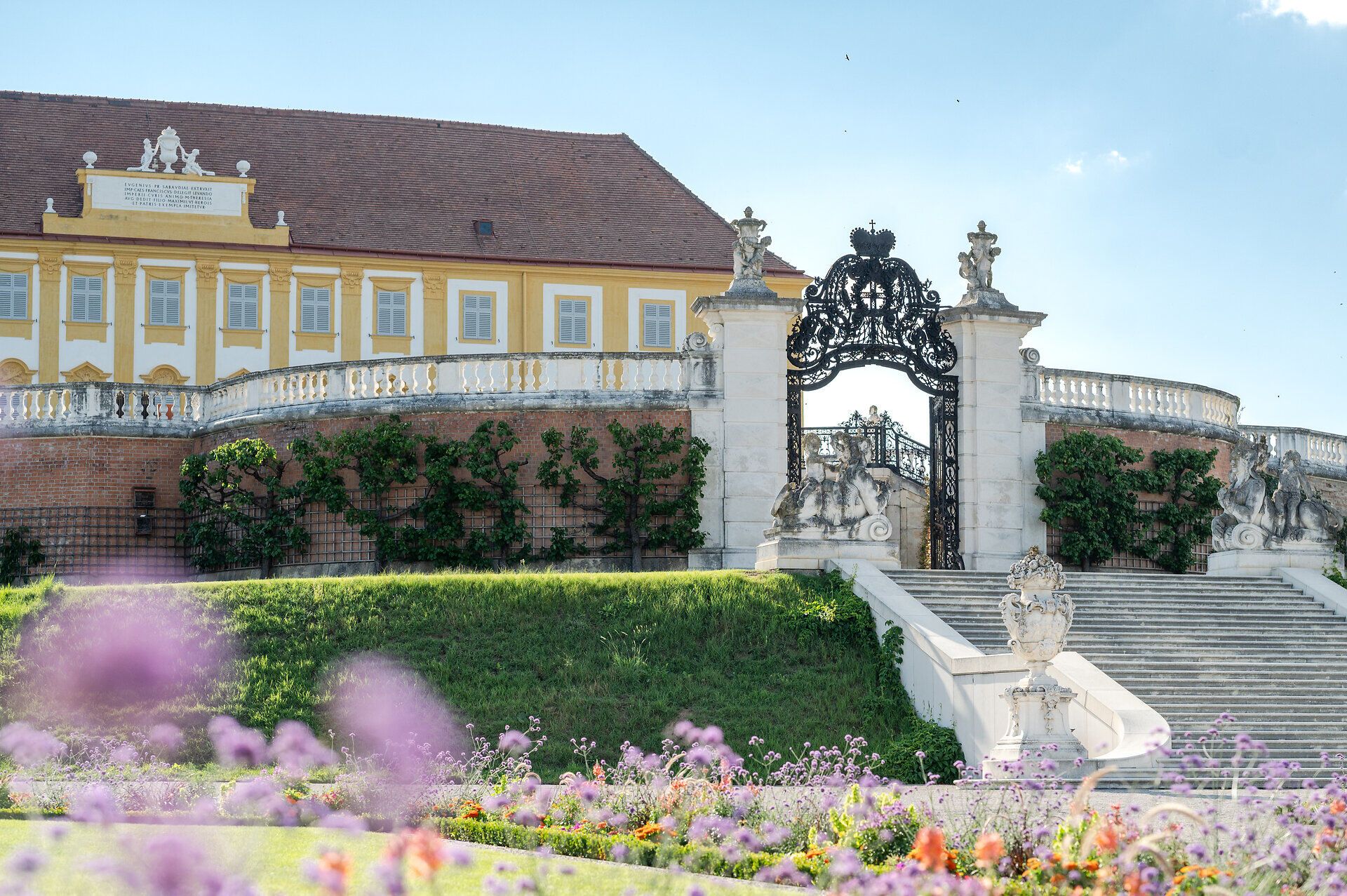 Schloss Hof mit seiner barocken Fassade und dem geometrisch gestalteten Garten im Vordergrund.