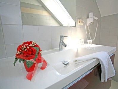 Ein Badezimmerwaschbecken mit Handtuch, Fön und Blumendekoration.