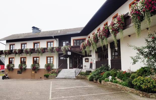Ein traditioneller Landgasthof mit Blumen geschmückten Balkonen und einem Eingang mit Treppe.