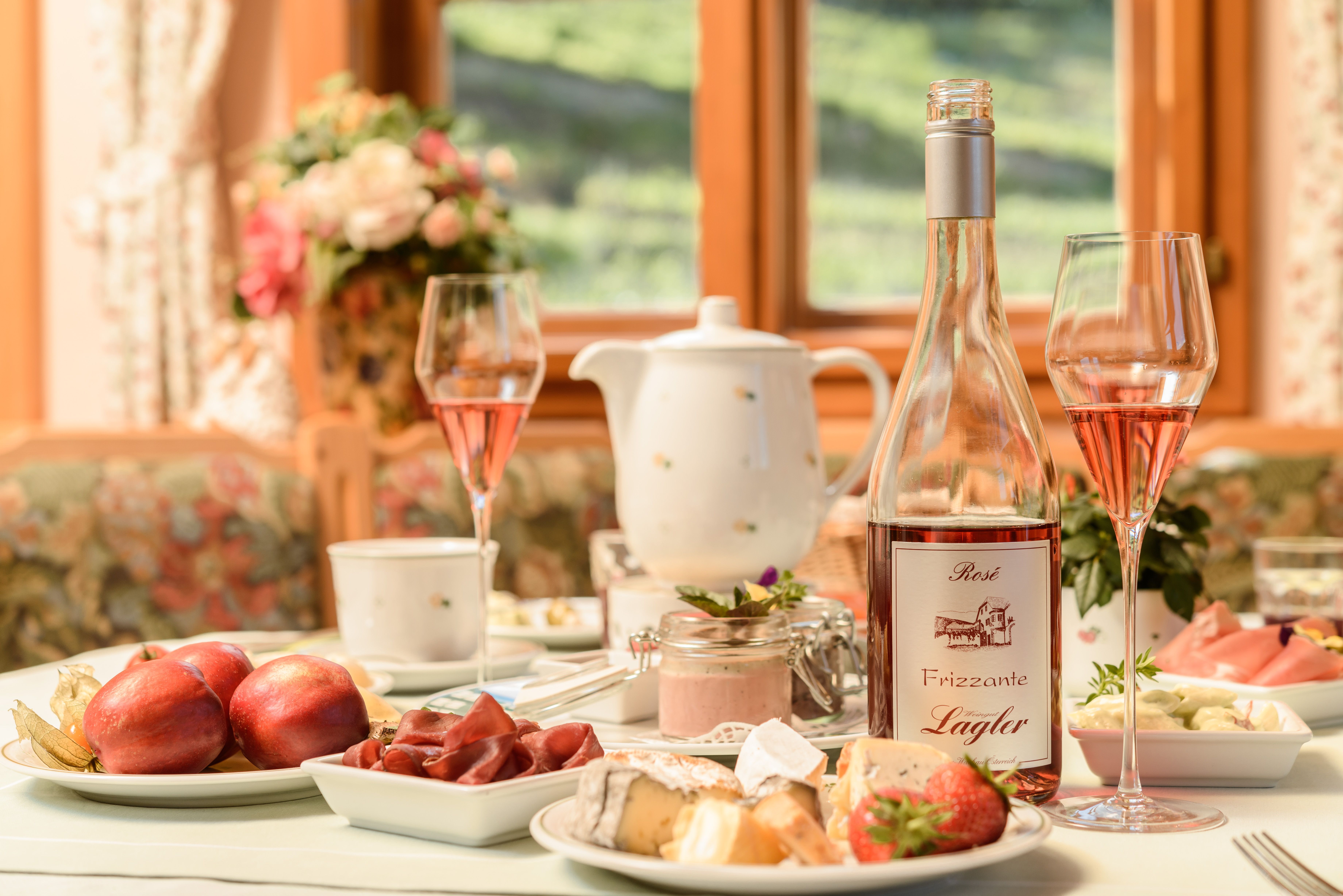 Frühstückstisch mit Obst und Käse und einer Flasche Frizzante
