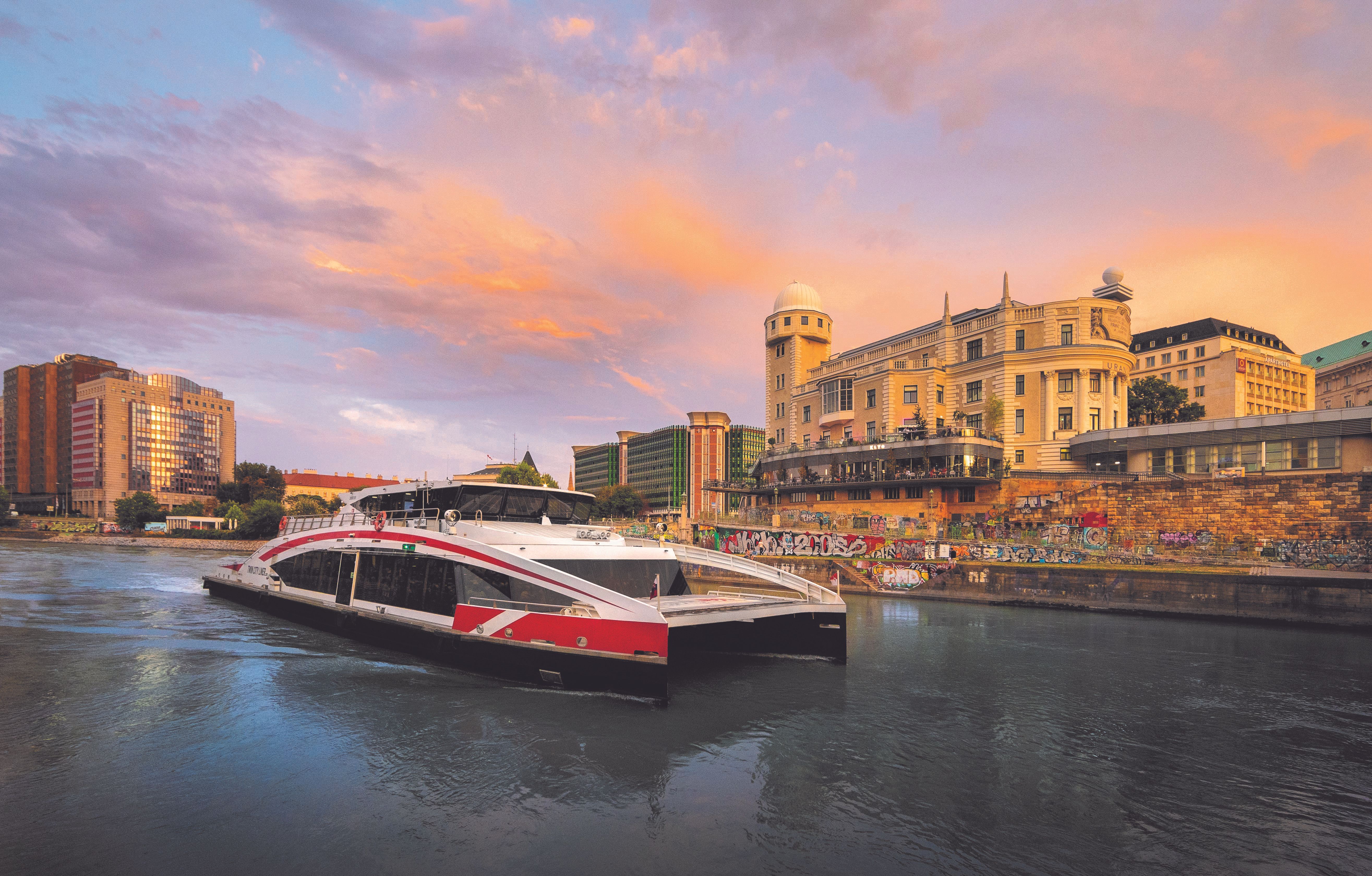 Schiff auf dem Wasser in Wien und im Hintergrund Gebäude. 