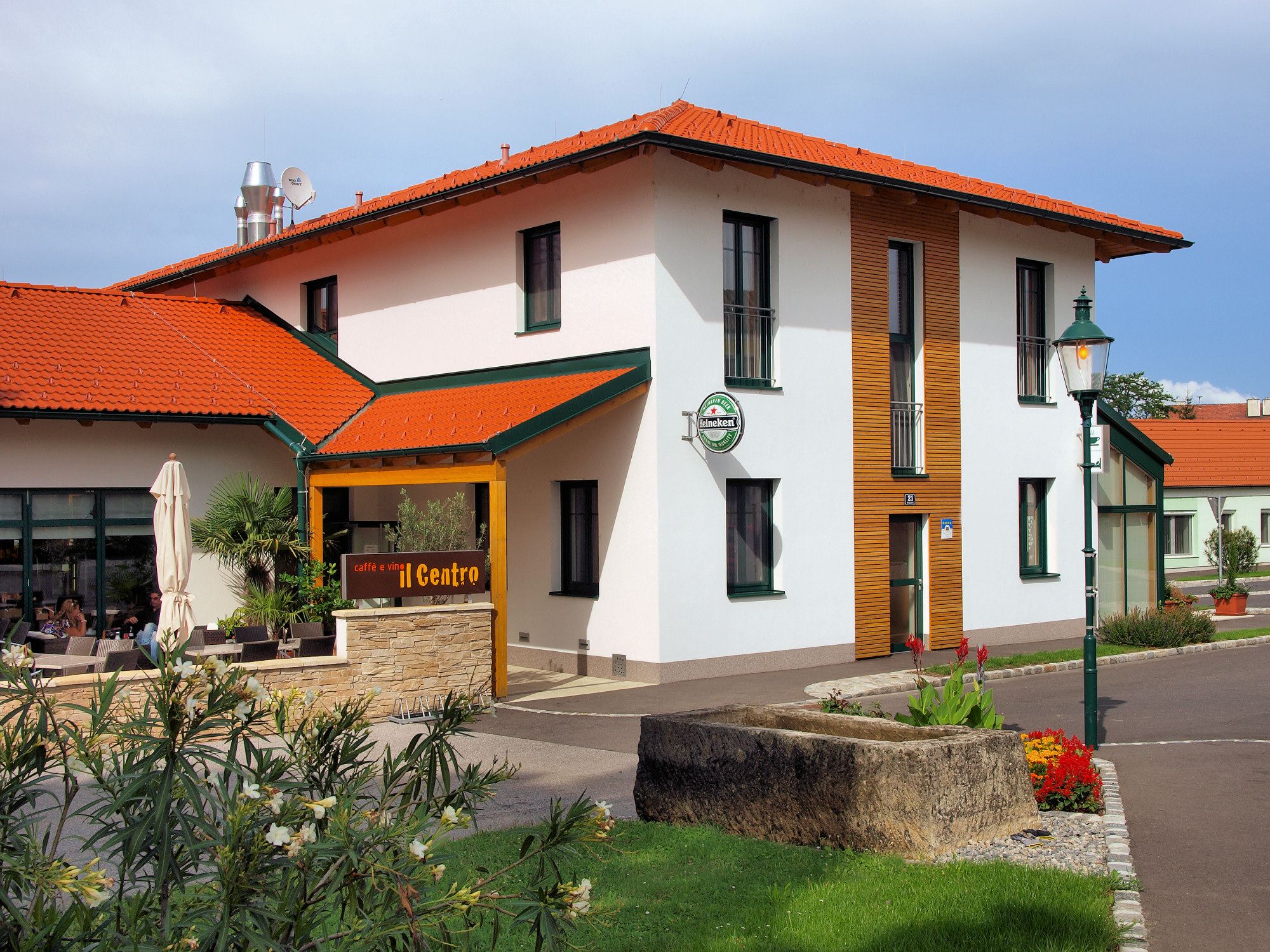 Außenansicht eines Gebäudes mit rotem Dach und Terrasse, beschriftet mit 'caffè e vini Centro'.