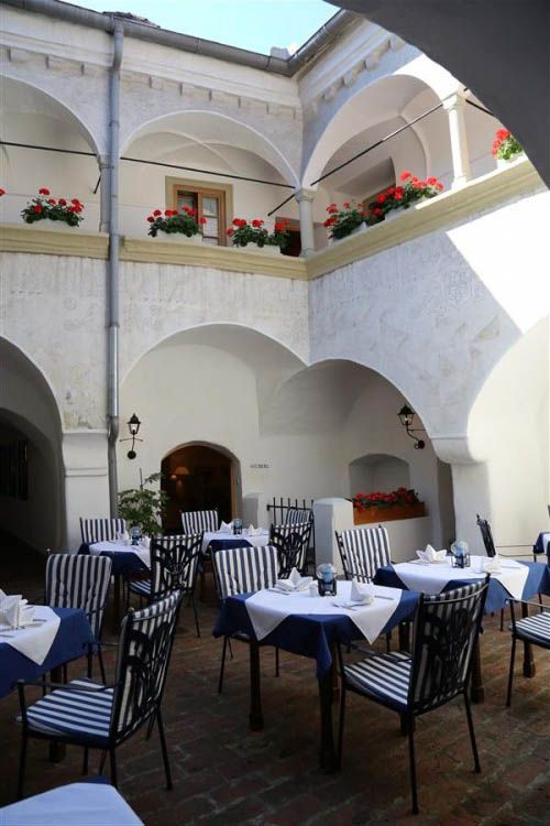 Innenhof eines Gasthofs mit gedeckten Tischen und Blumen.