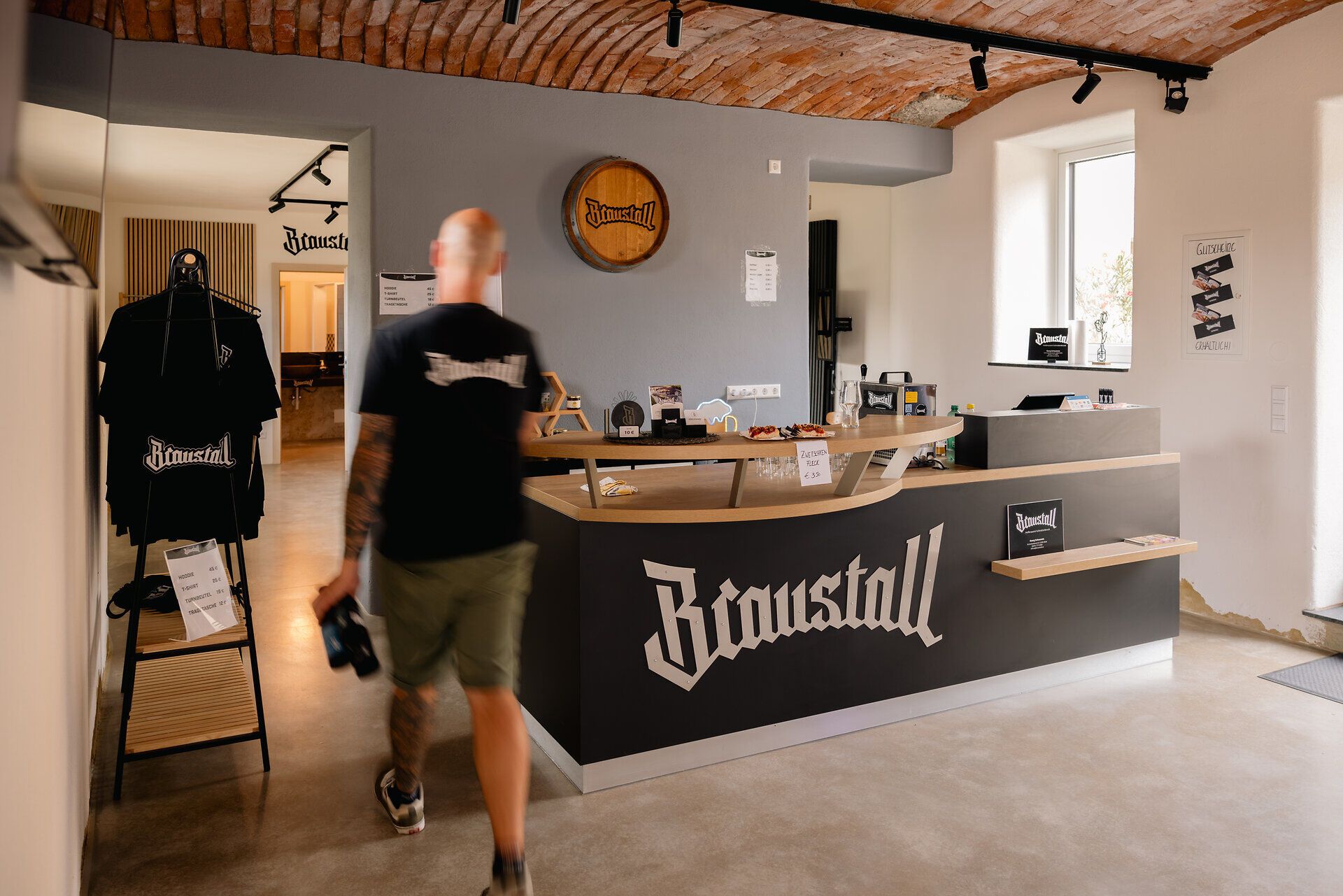 Mann geht mit Bierflaschen durch den Verkaufsraum des Braustalls.
