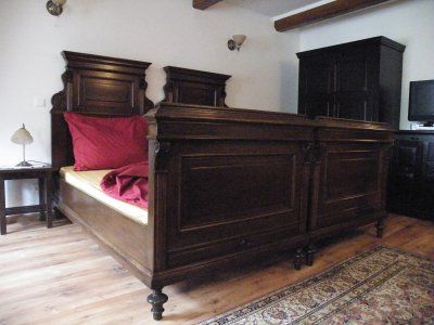 Holzbett in rustikalem Schlafzimmer mit roter Bettwäsche.