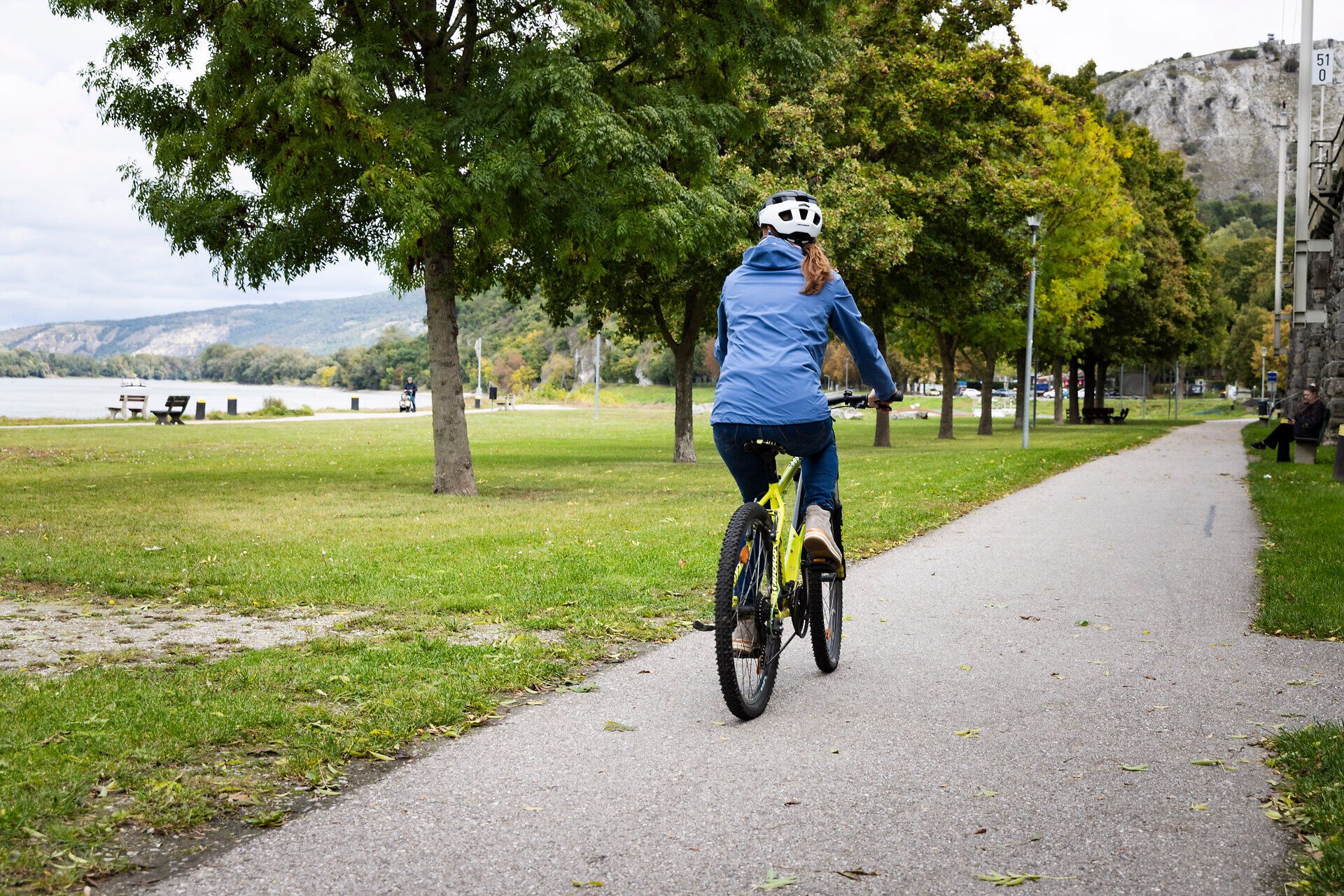 Eine Frau fährt mit dem Fahrrad am Donauradweg bei Hainburg.