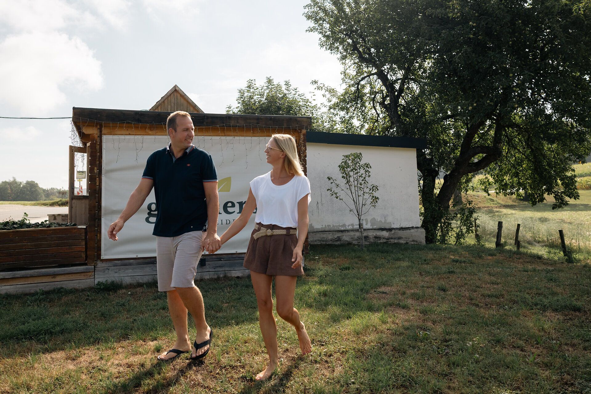 Mann und Frau gehen Hand in Hand über eine Wiese.