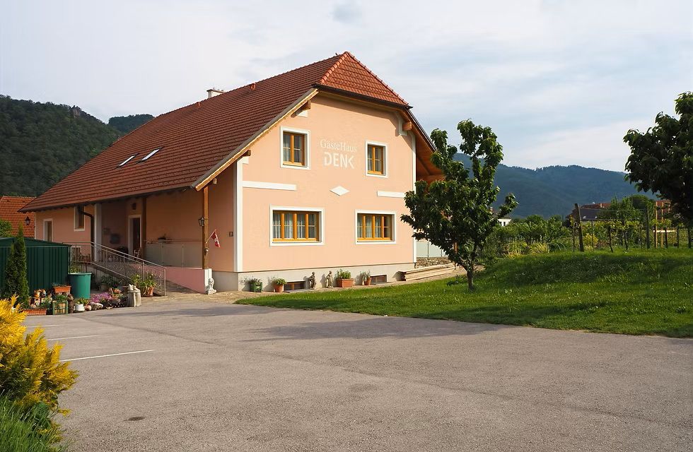 oranges Einfamilienhaus mit asphaltierter Parkfläche davor