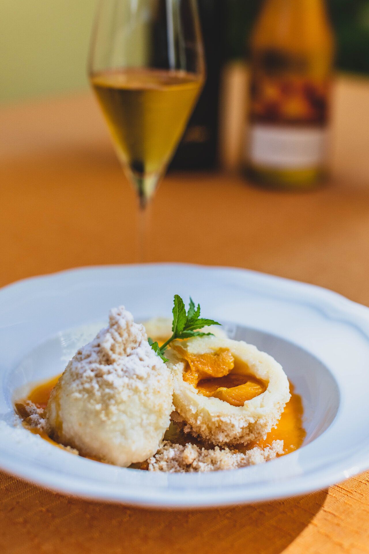 Genießen Sie die süßen Marillenknödel, die in einer köstlichen Sauce serviert werden, während ein Glas erfrischender Cider auf dem Tisch steht. Diese Spezialität bringt den Geschmack des Sommers direkt auf den Teller und lädt dazu ein, die kulinarischen Köstlichkeiten der Region zu entdecken.