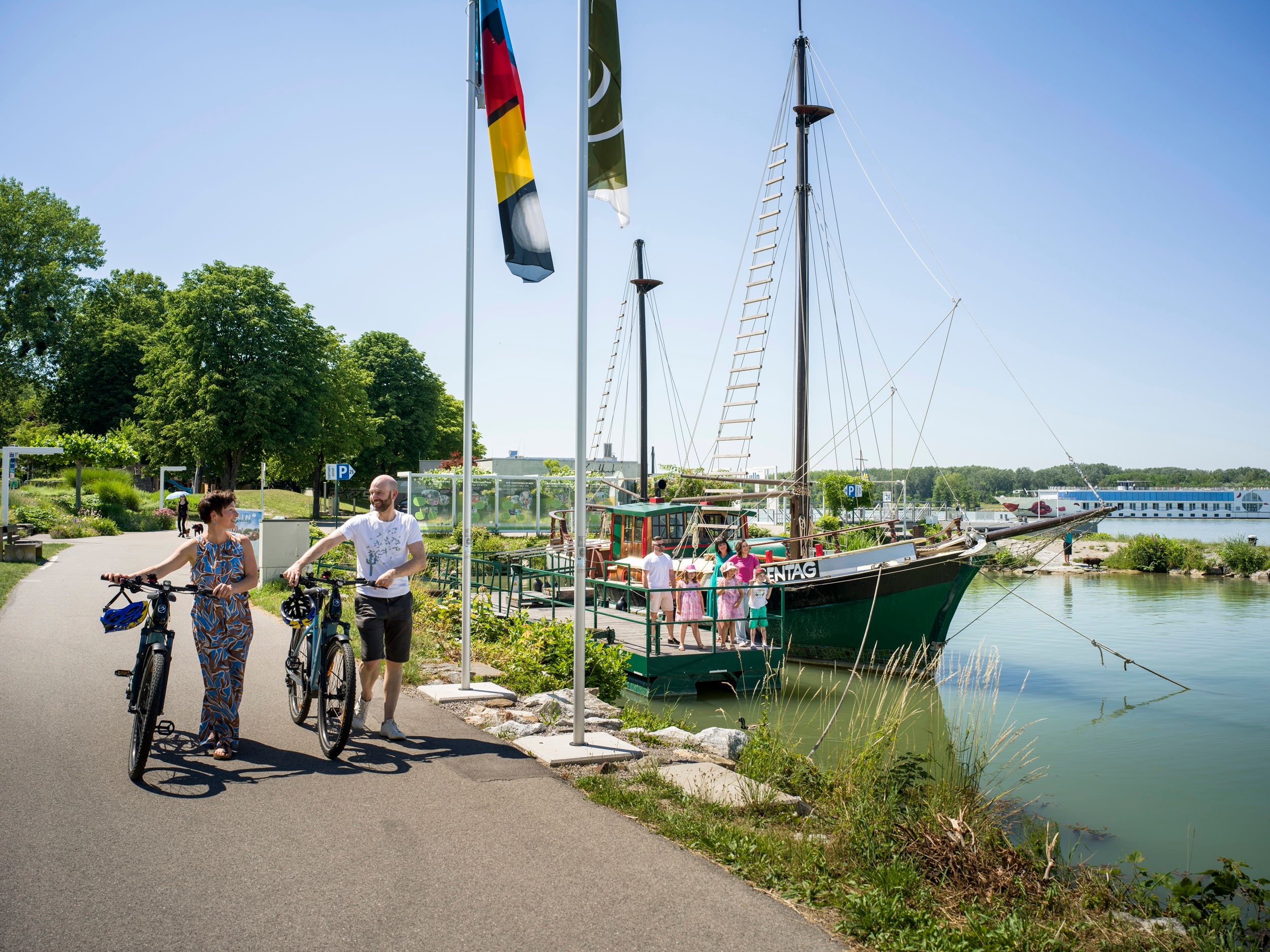 historisches Schiff im Wasser mit Radfahrern am Donauradweg 