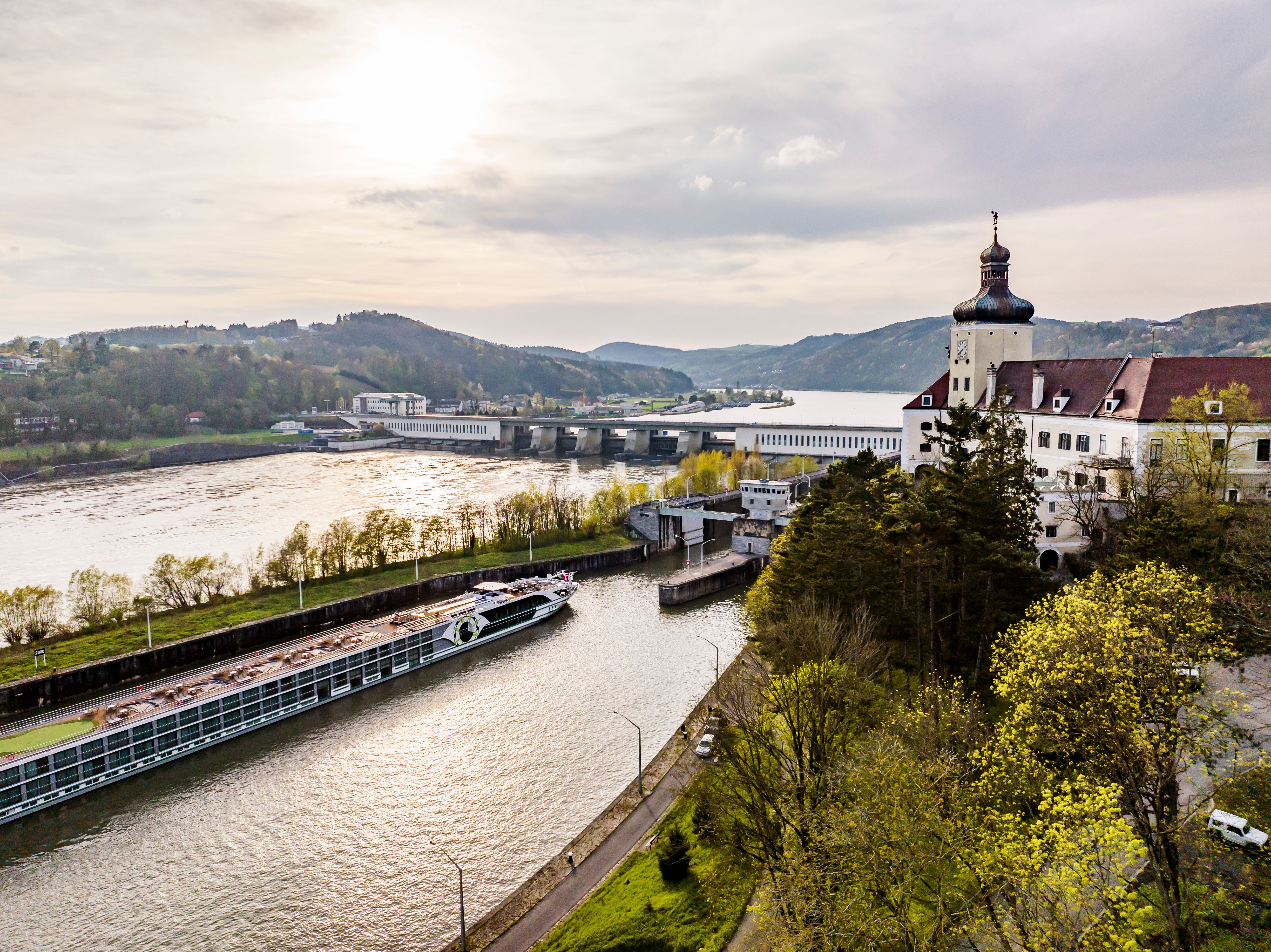 Ybbs-Persenbeug power station on a sunny day with the river and wooded hills in the background.