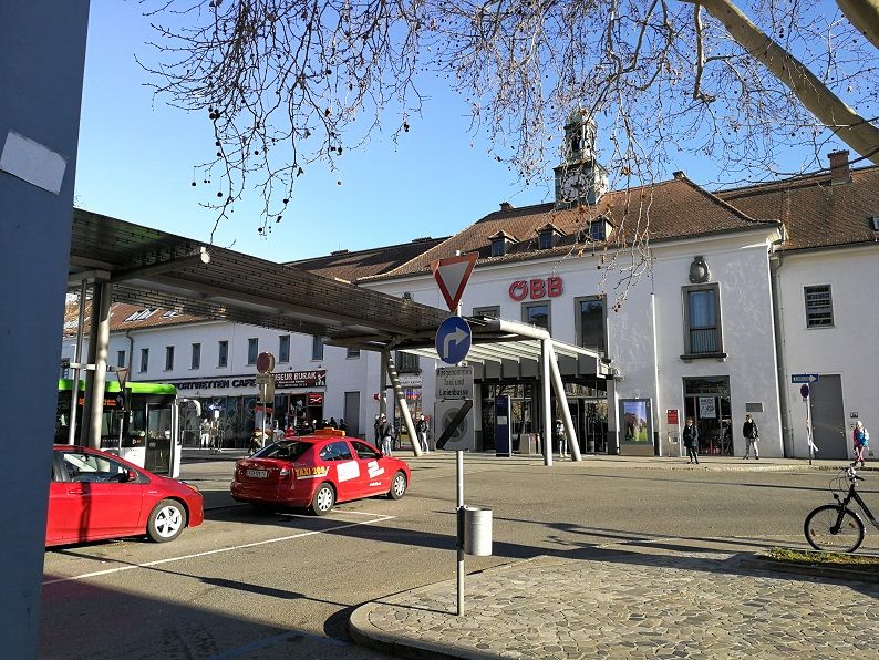 Bahnhof Krems an der Donau mit ÖBB-Logo, Autos und Fußgängern.