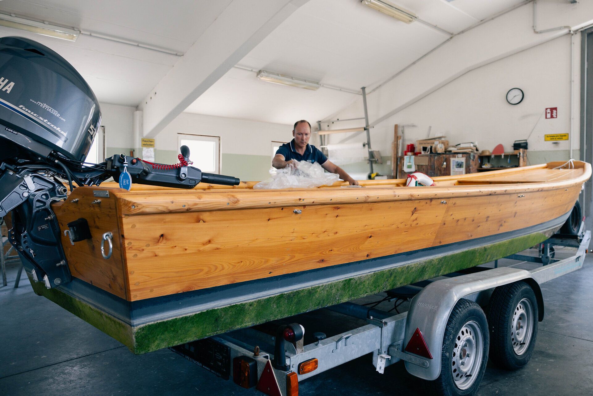 Ein Mann lehnt in der Werft an einem Holzboot.