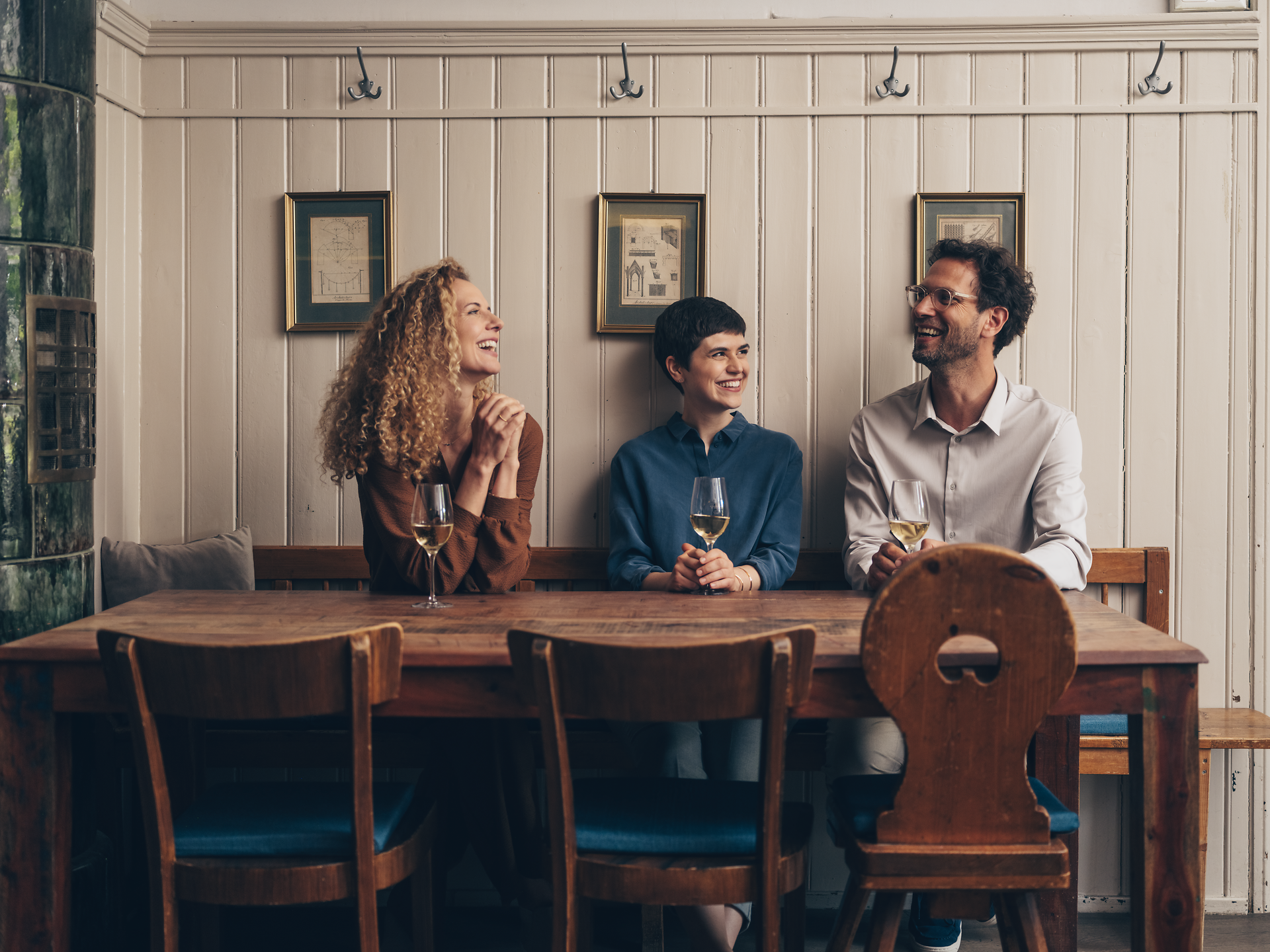 In einem einladenden Wirtshaus sitzen drei Freunde zusammen und genießen ein Glas Wein. Die warme Atmosphäre und das Lachen schaffen eine perfekte Kulisse für gesellige Stunden. Hier wird die Wirtshauskultur Niederösterreichs lebendig.