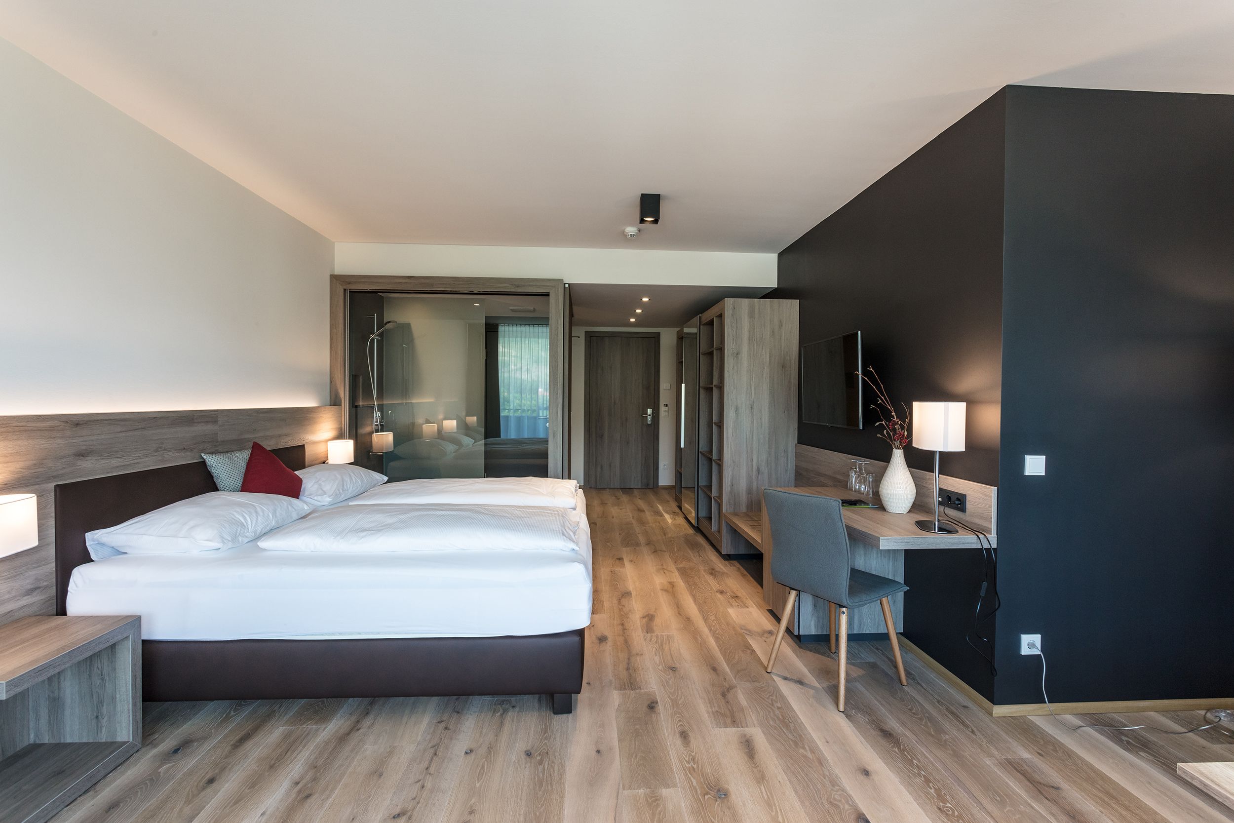 Modernes Hotelzimmer mit Doppelbett, Schreibtisch und Holzfußboden.