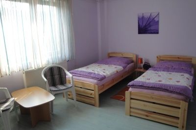 Ein einfach eingerichtetes Zimmer mit zwei Einzelbetten, einem kleinen Tisch und zwei Stühlen.