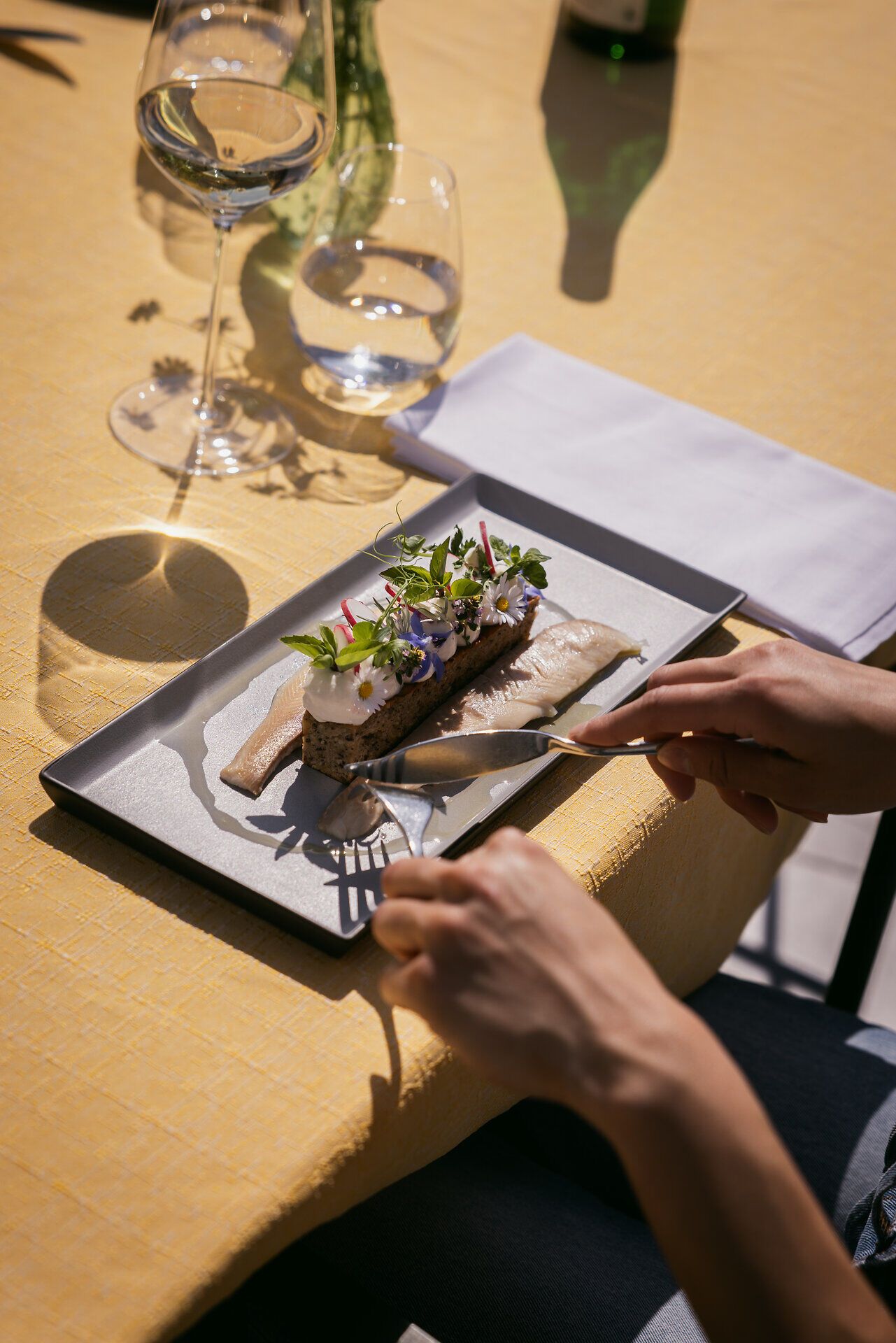 Dekorierte Fischfilets werden mit Messer und Gabel angeschnitten.